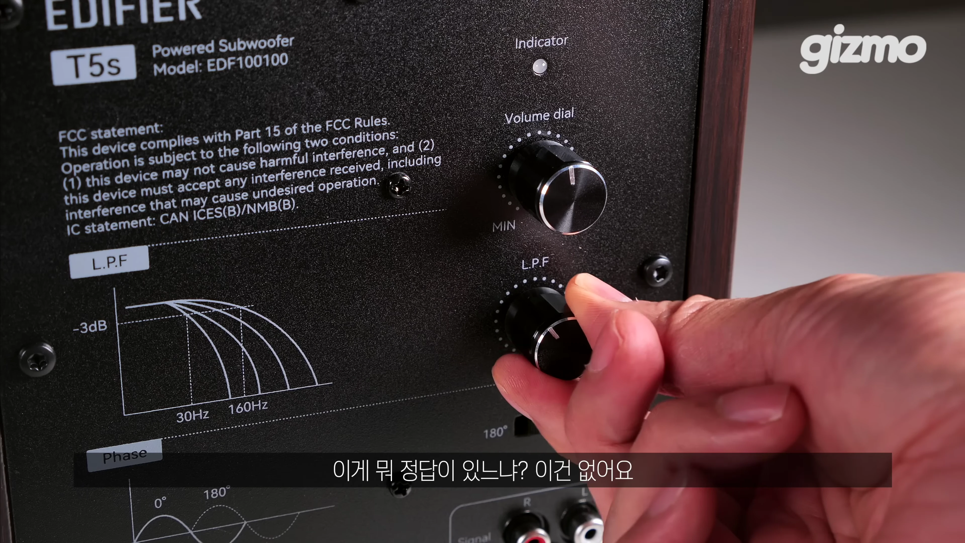 에디파이어 T5S 서브우퍼 뒷면의 볼륨 및 L.P.F 다이얼을 손으로 조절하는 근접 촬영 장면