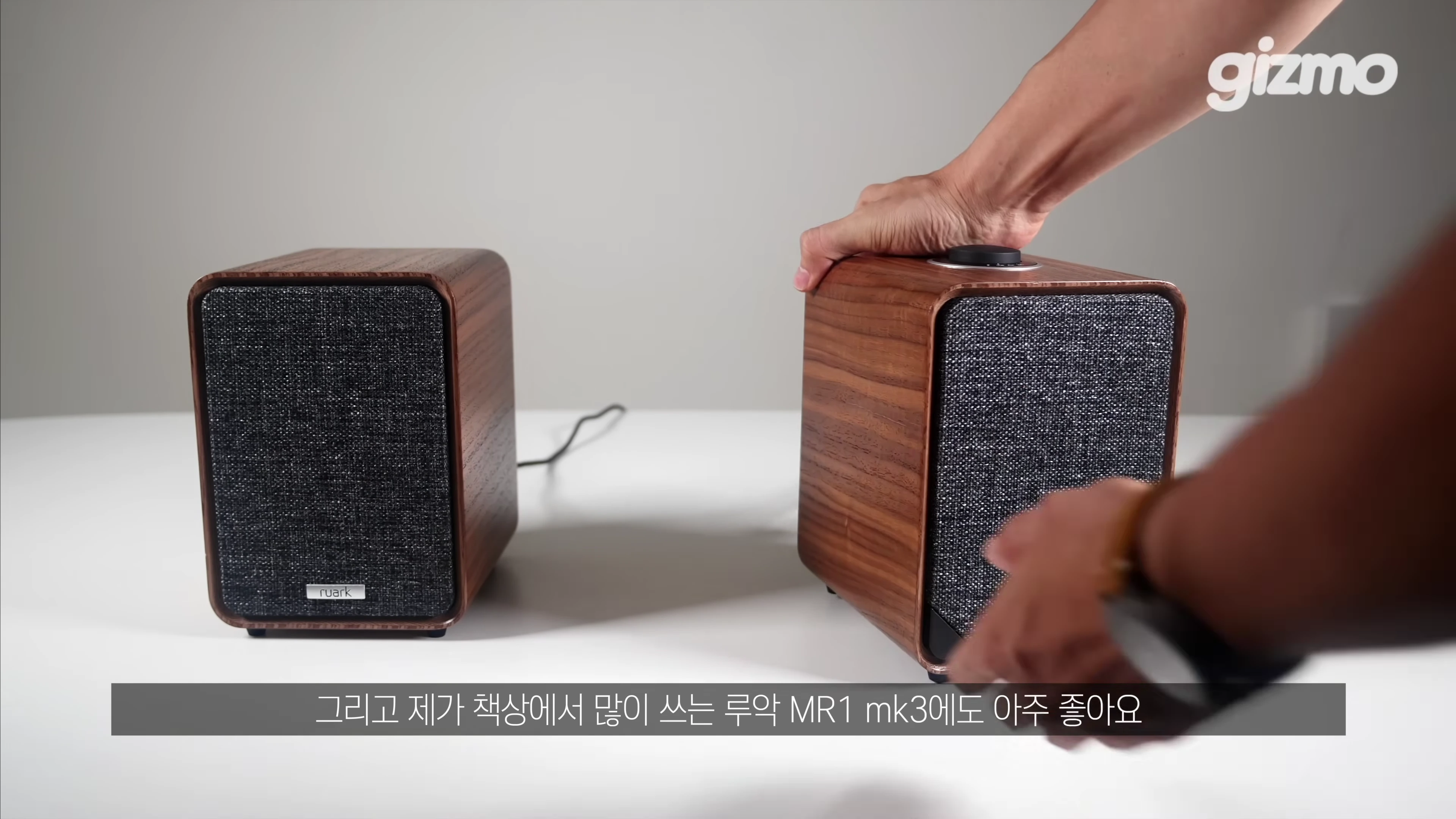 테이블 위에 놓인 루악 MR1 mk3 스피커를 손으로 만지는 모습