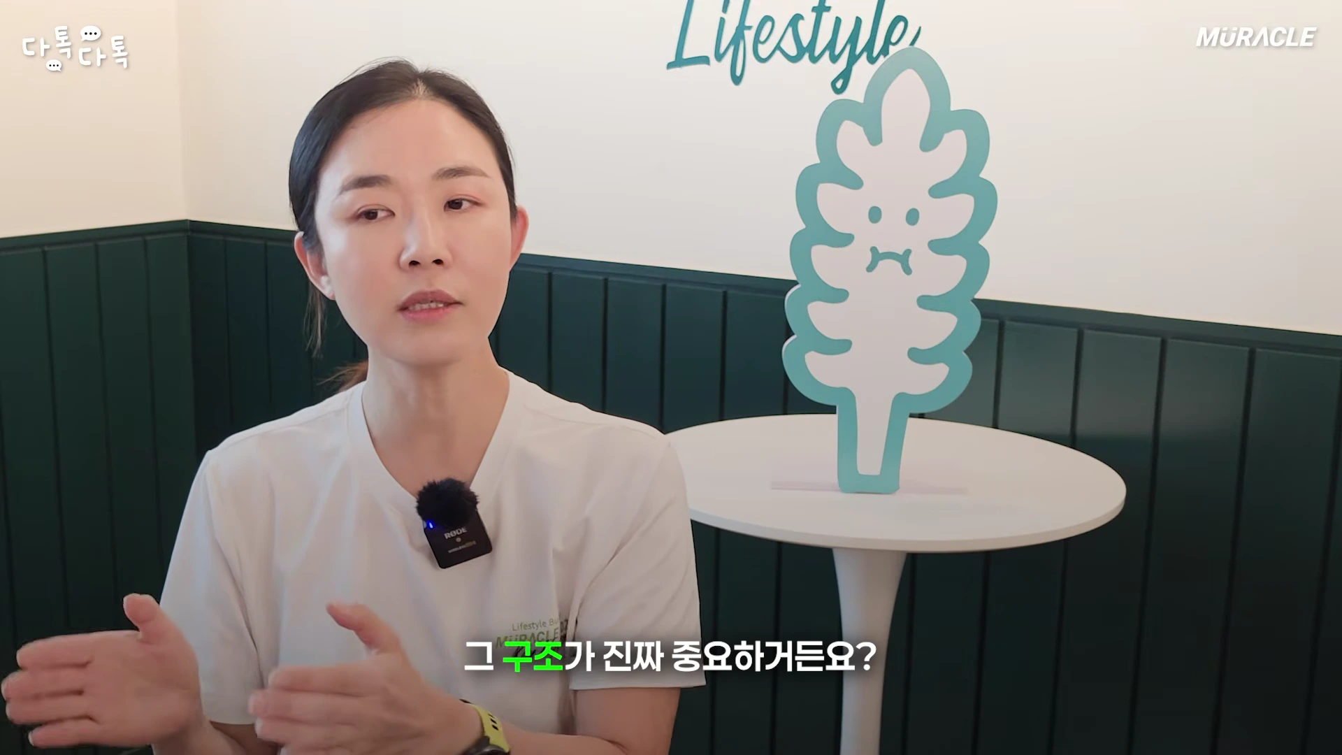 흰색 티셔츠를 입은 여성이 손짓하며 이야기하는 토크 장면