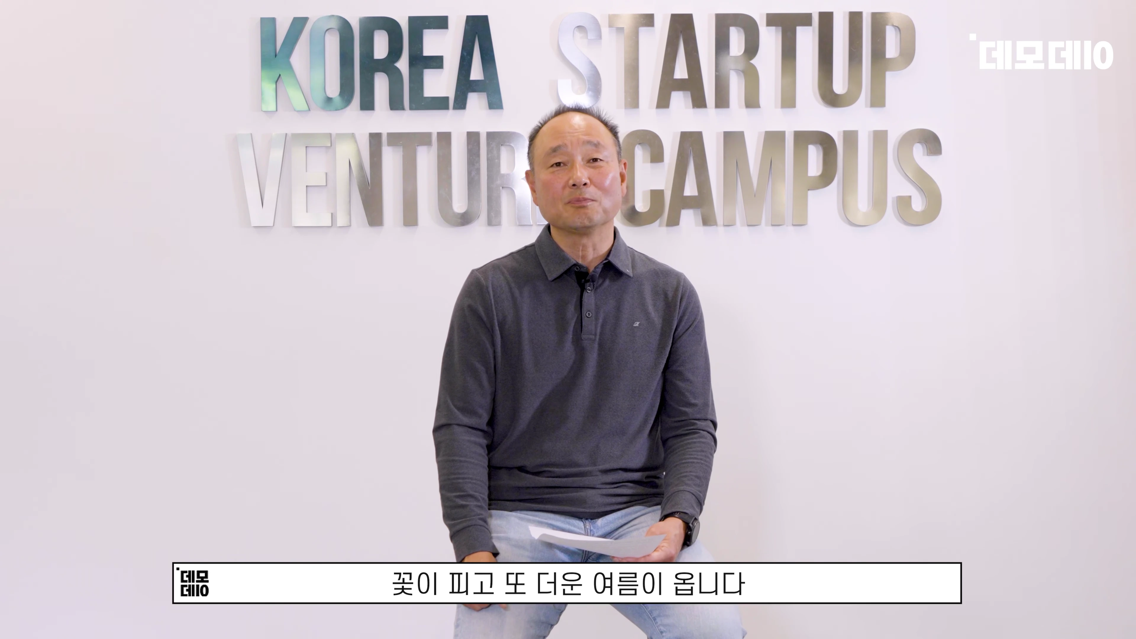 스타트업 캠퍼스 로고가 적힌 벽 앞에 앉아 있는 중년 남성