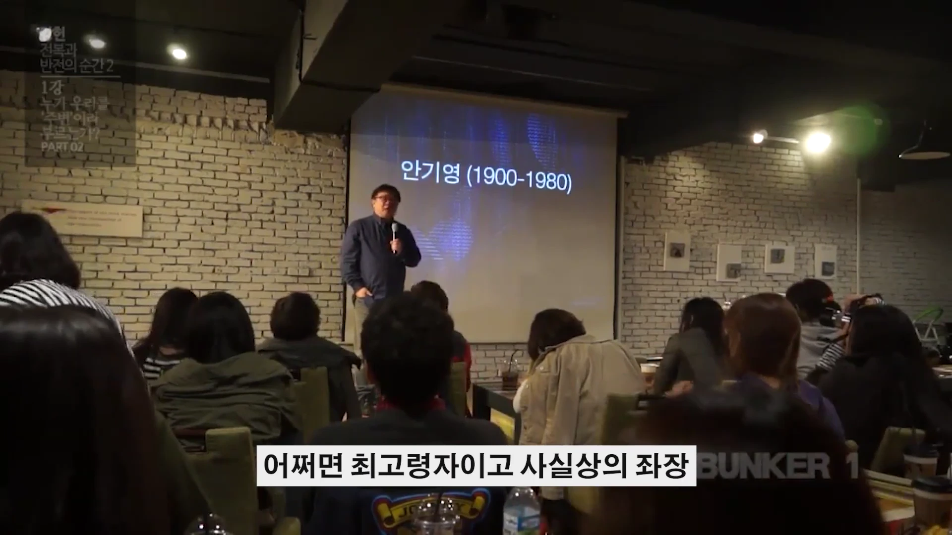 강연장에서 한 남성이 마이크를 잡고 서 있고, 뒤편 스크린에는 '안기영(1900-1980)'이라는 글자가 떠 있다.