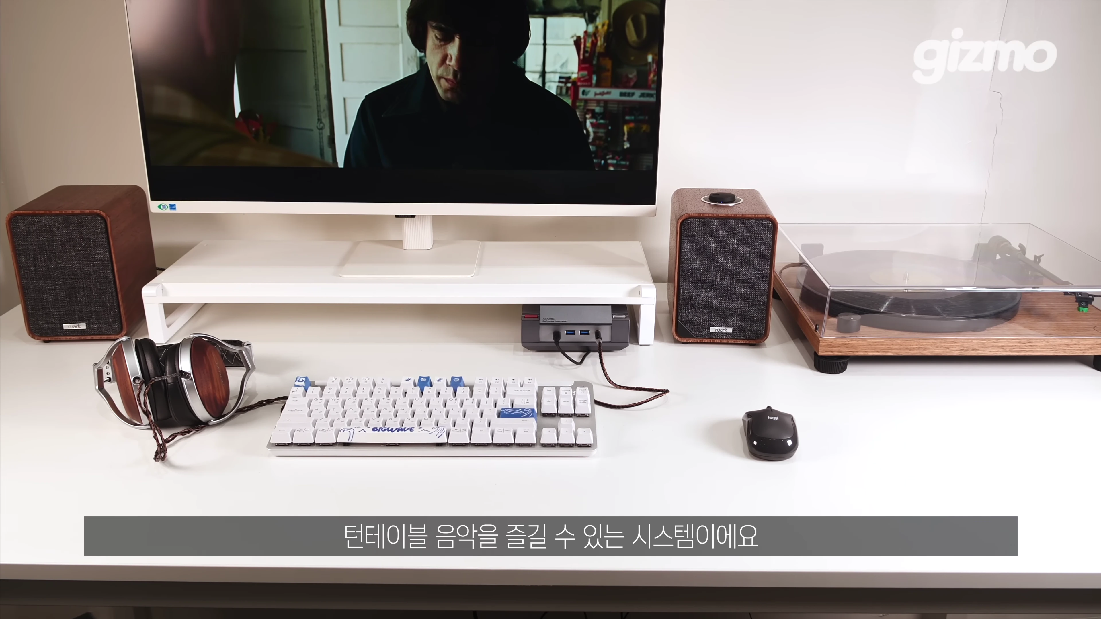 책상 위에 놓인 원목 스피커, 턴테이블, 헤드폰과 모니터가 보이는 데스크테리어 구성