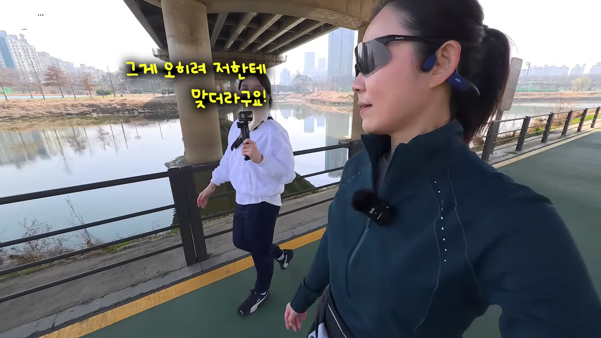 야외 산책로에서 운동복을 입고 걷는 두 여성의 모습이 담긴 영상 캡처 화면