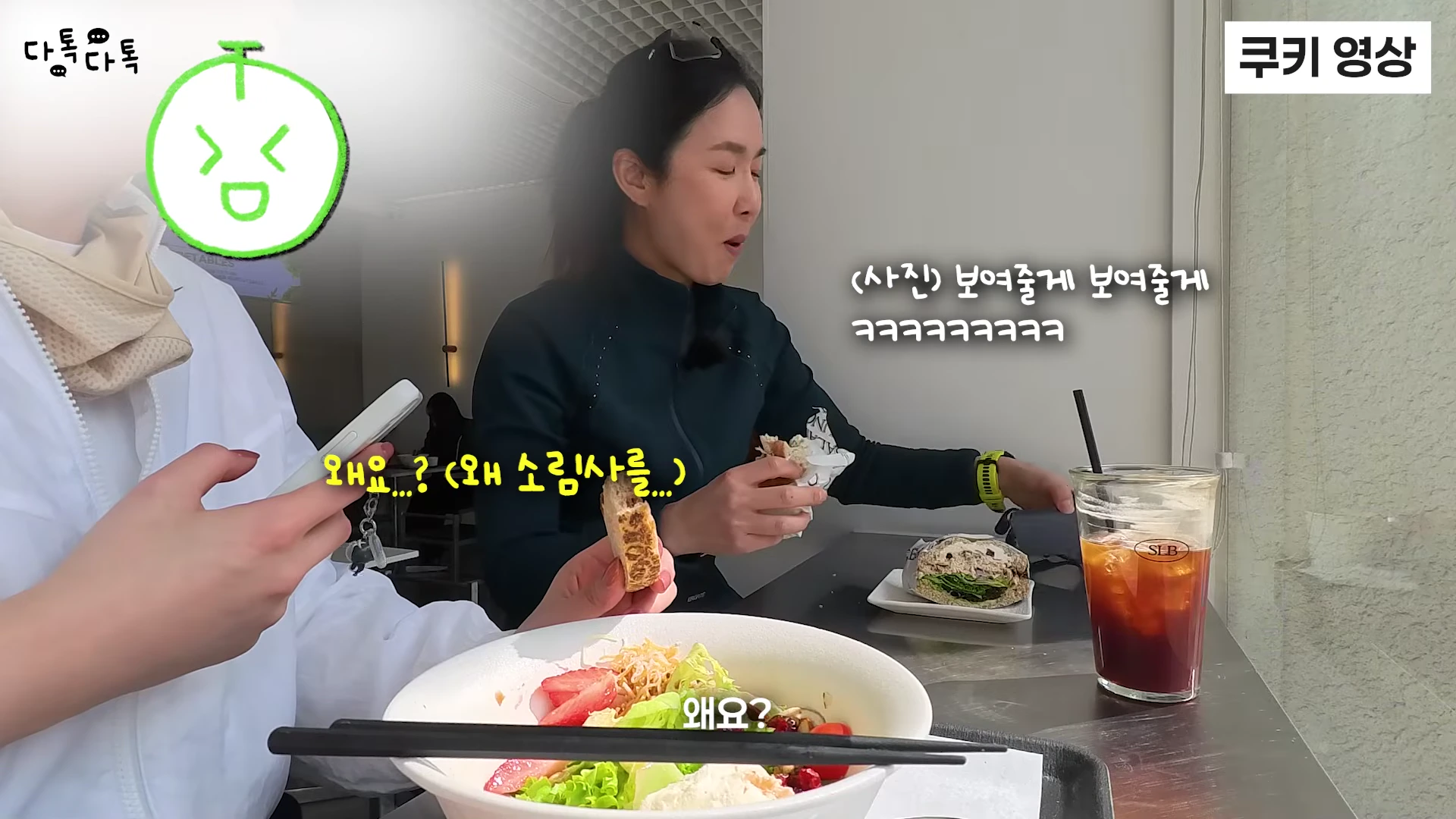 카페 테이블에 앉아 샌드위치를 먹으며 대화하는 두 여성의 모습이 담긴 영상 캡처 화면