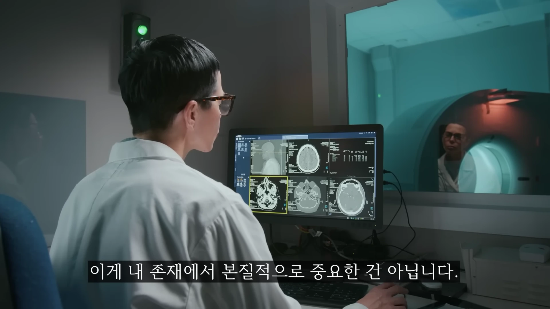 흰 가운을 입은 연구원이 모니터에 띄워진 뇌 단층 촬영 영상을 살펴보고 있다.