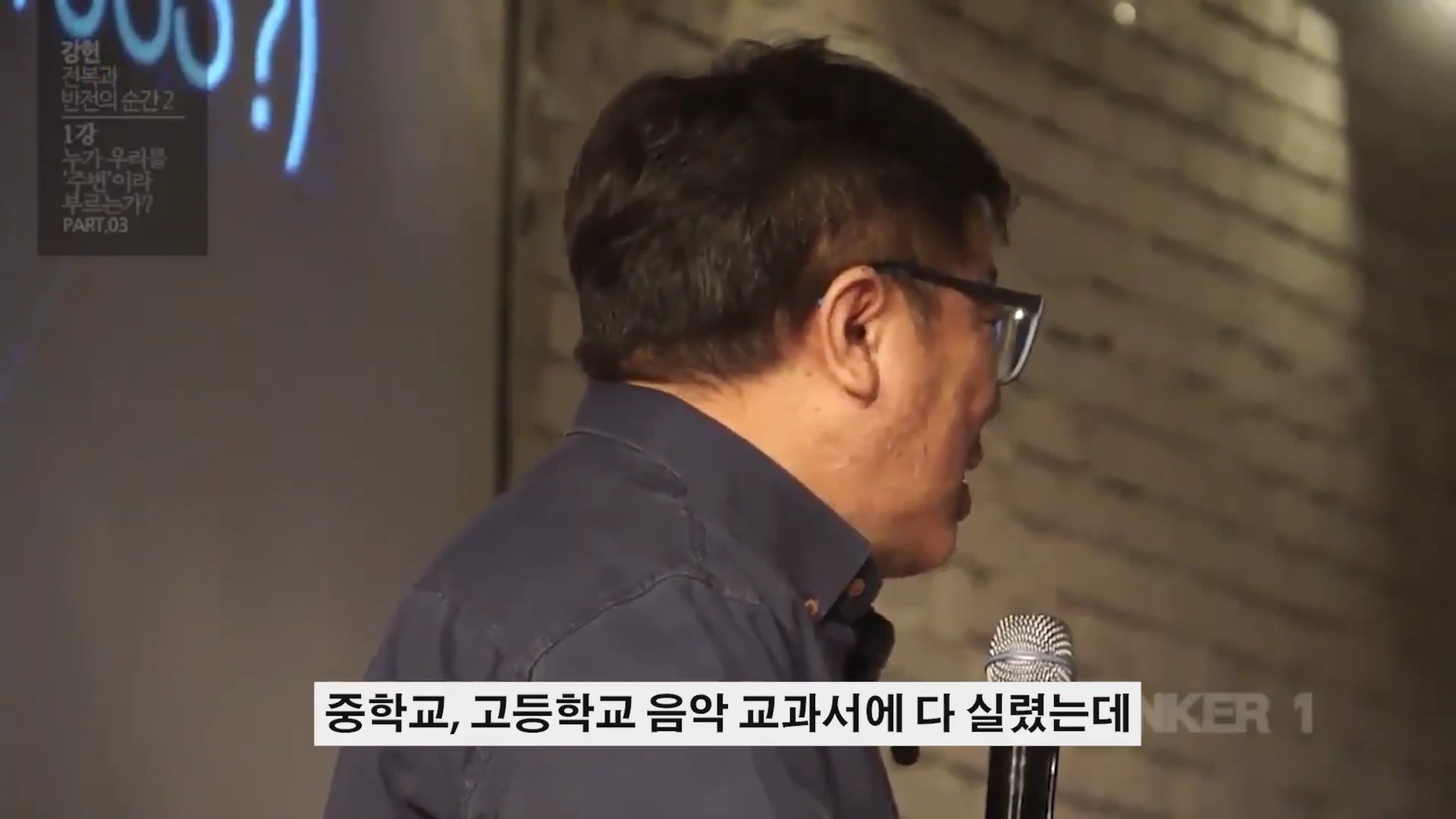 안경을 쓴 남성이 마이크를 잡고 강연하는 옆모습이 담긴 영상 캡처 화면