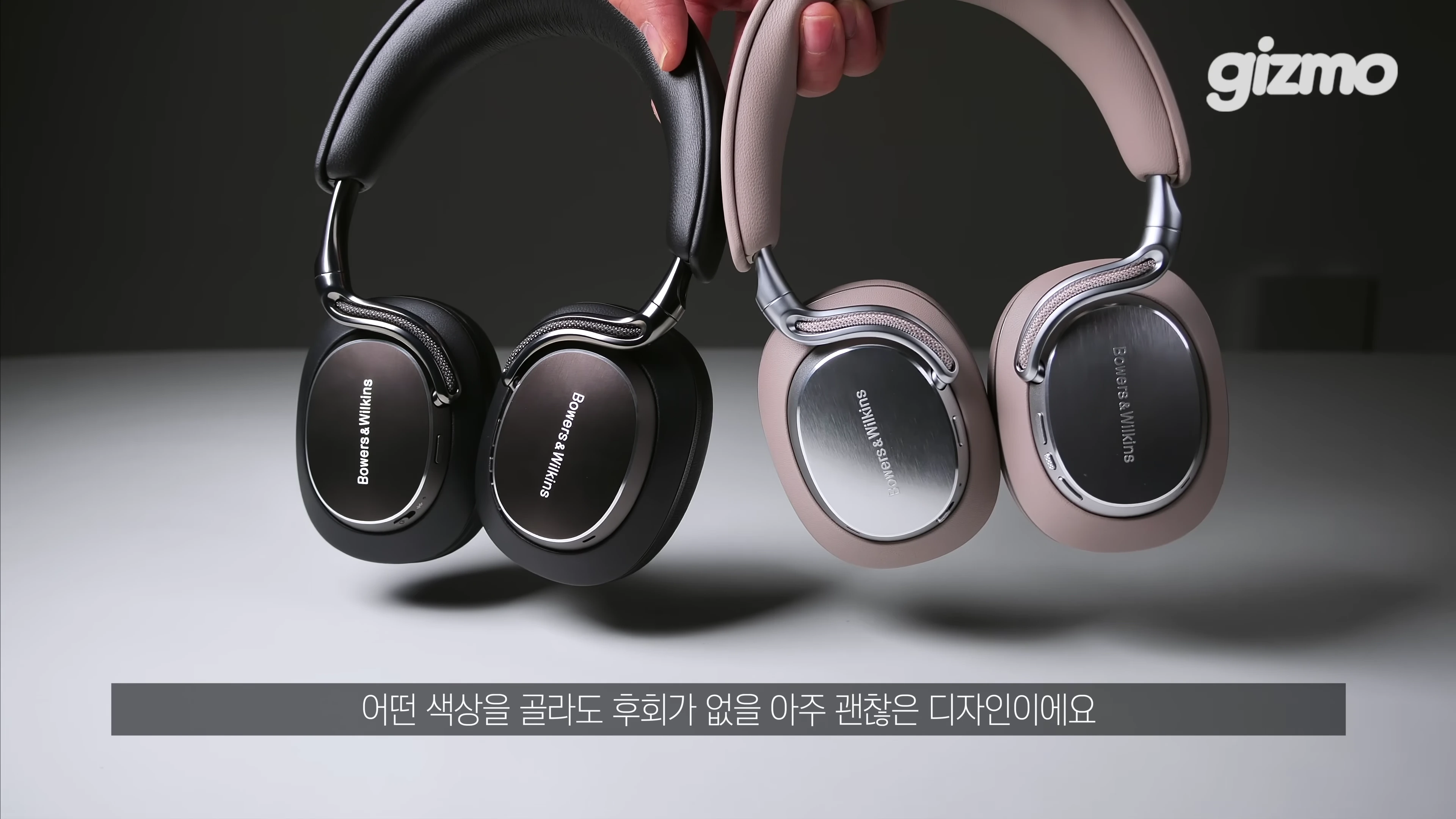 손으로 들고 있는 블랙과 웜스톤 색상의 바워스앤윌킨스 헤드폰 두 대
