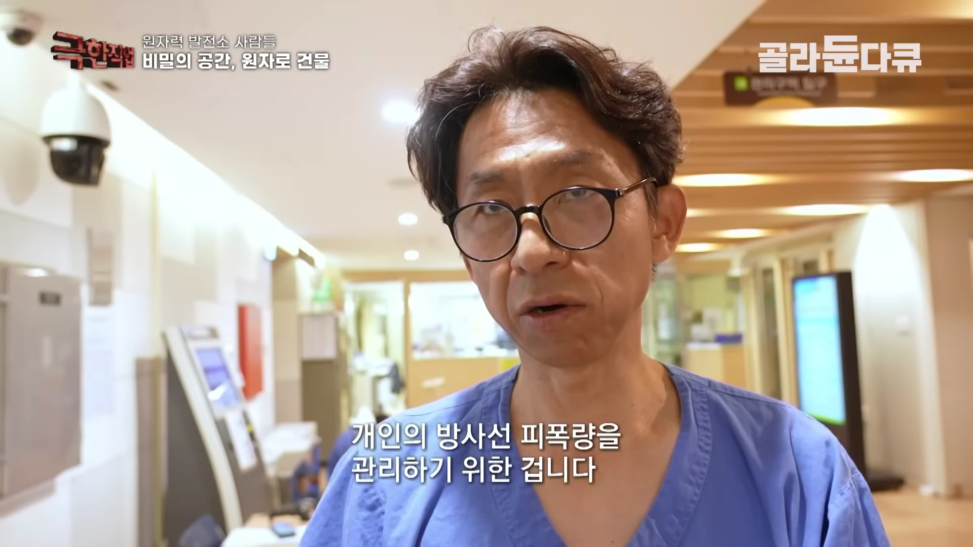 안경을 쓴 중년 남성이 파란색 작업복을 입고 실내에서 인터뷰하는 모습