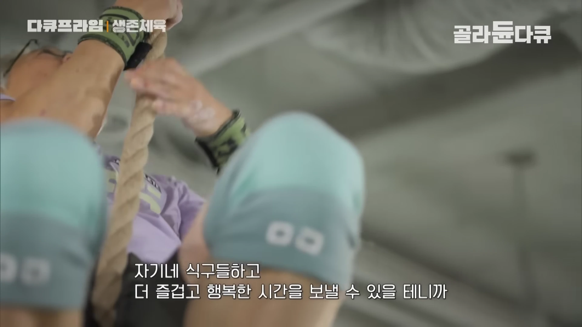 실내 체육관에서 중년 남성이 밧줄을 잡고 위로 올라가는 모습