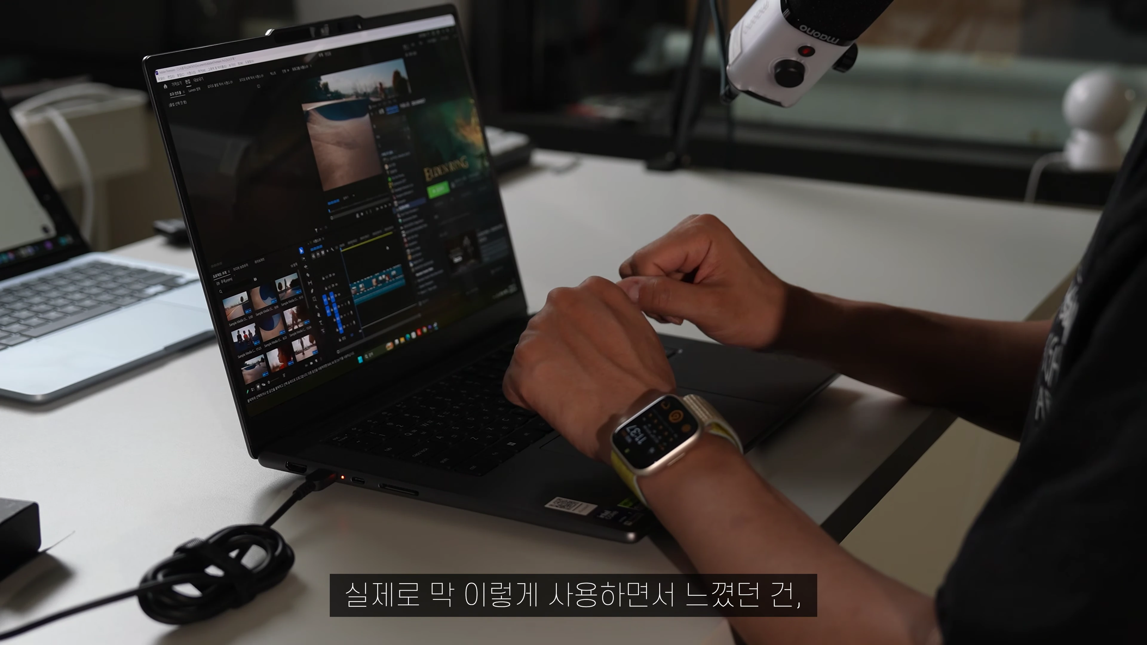 책상 위에서 노트북으로 영상 편집 프로그램을 사용하는 사람의 손과 화면