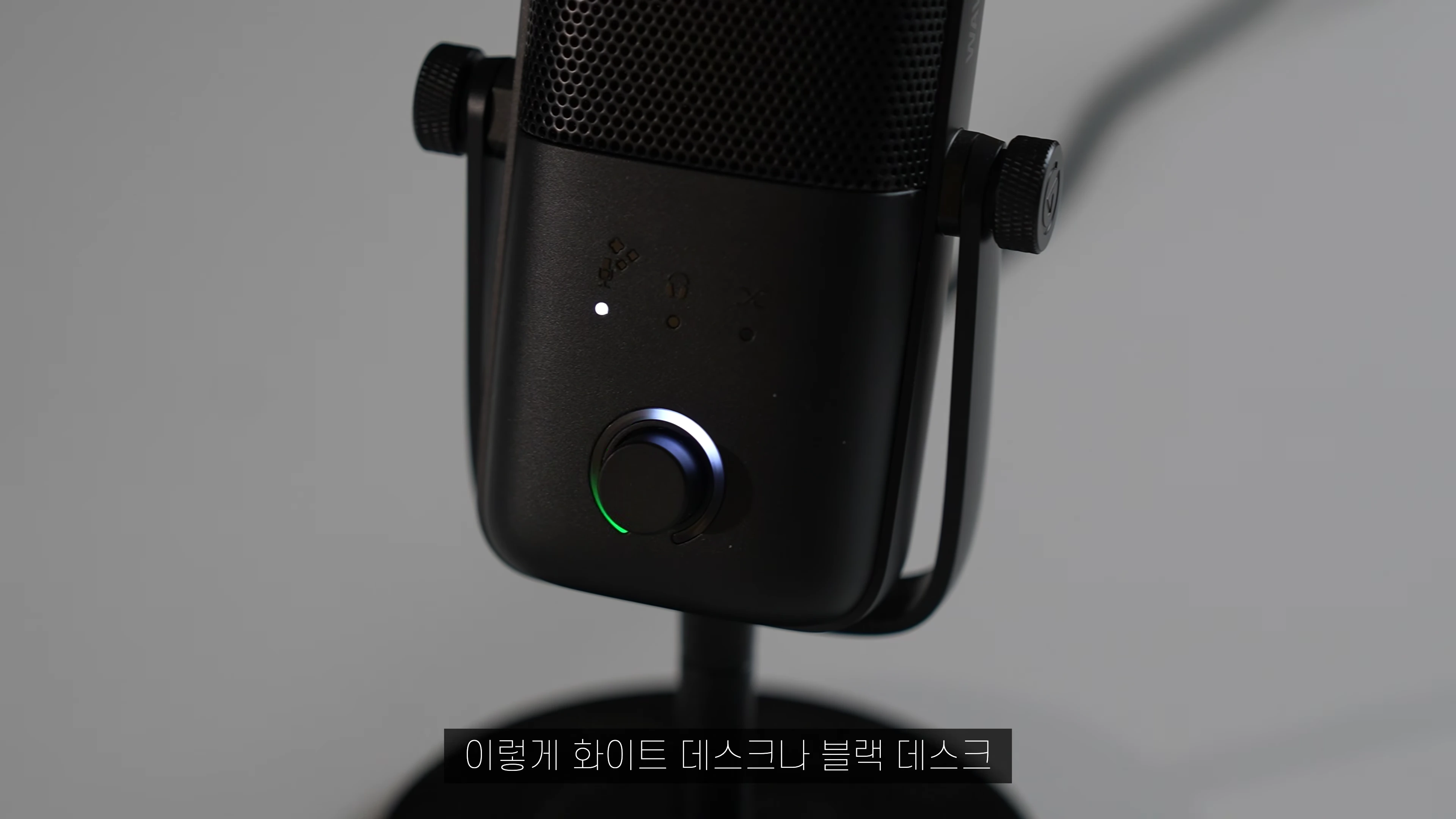 검은색 USB 마이크의 전면부와 조절 다이얼에 은은한 조명이 들어온 모습