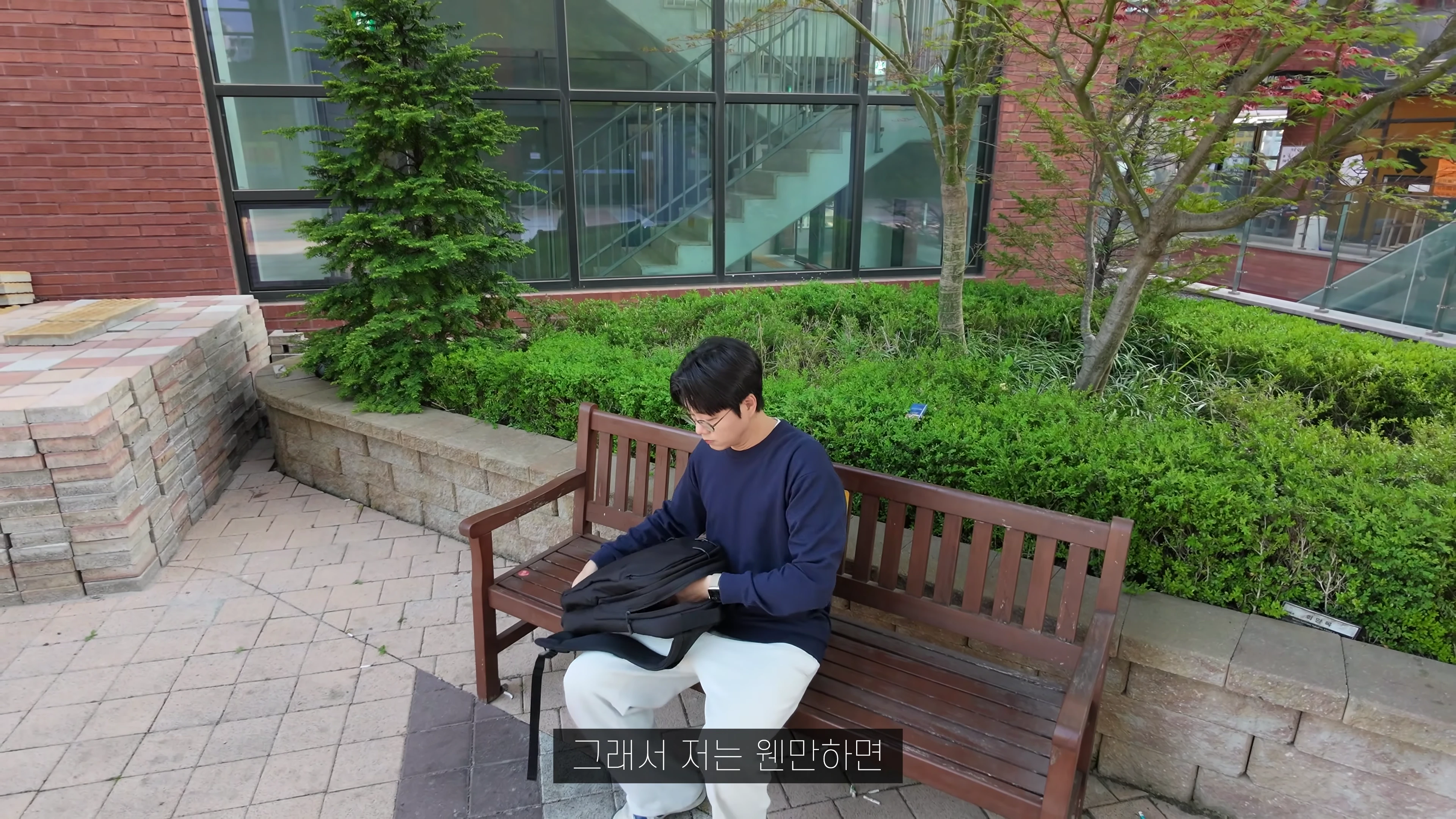 야외 벤치에 앉아 가방에서 노트북을 꺼내는 남성