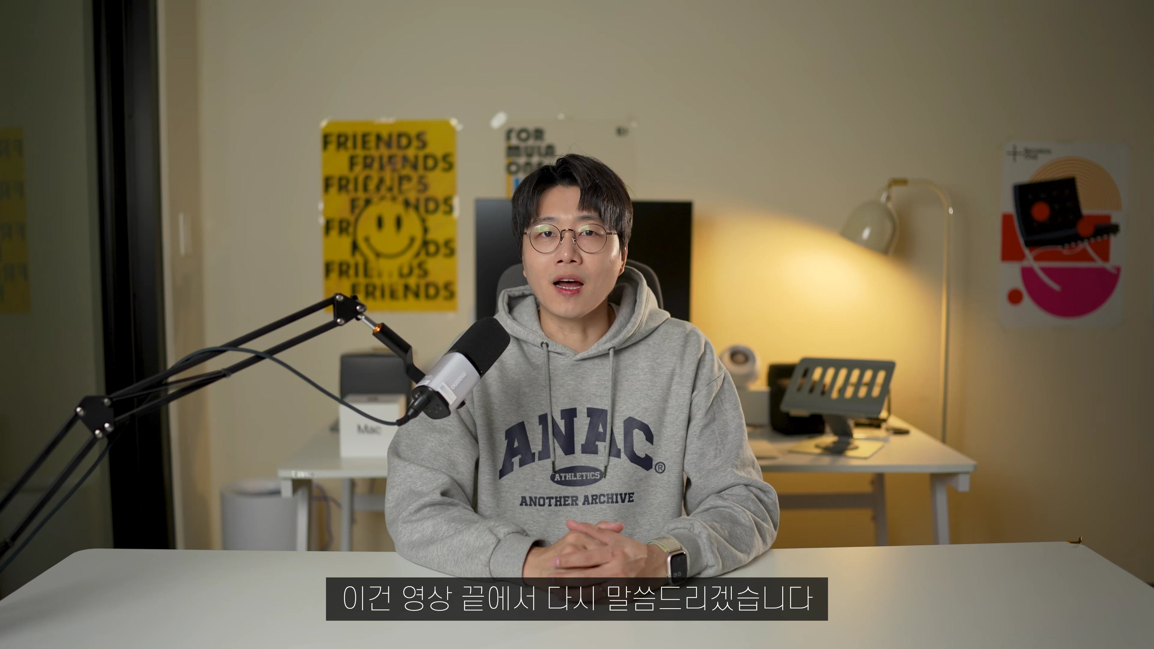 안경을 쓴 남성이 마이크 앞에 앉아 카메라를 보며 이야기하는 모습