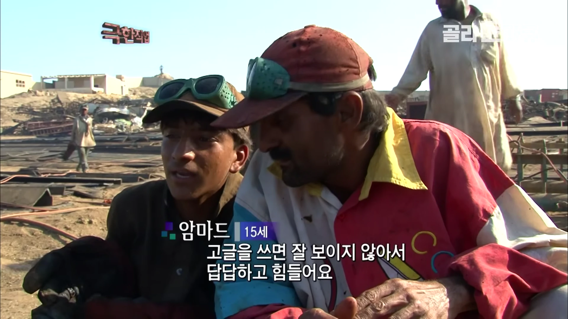 작업복을 입고 모자를 쓴 두 남성이 야외 작업장에서 인터뷰하는 모습