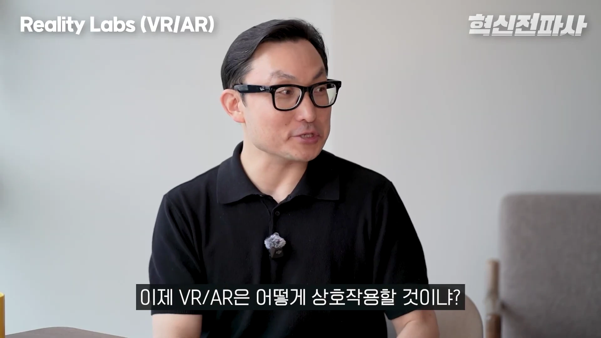 검은색 뿔테 안경을 쓴 남성이 인터뷰 중인 모습