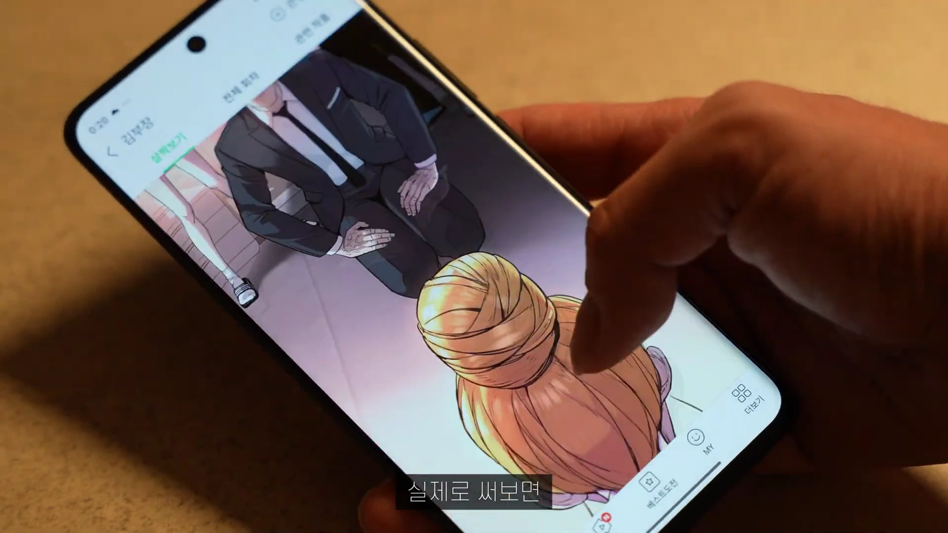 스마트폰으로 웹툰을 보고 있는 손과 화면