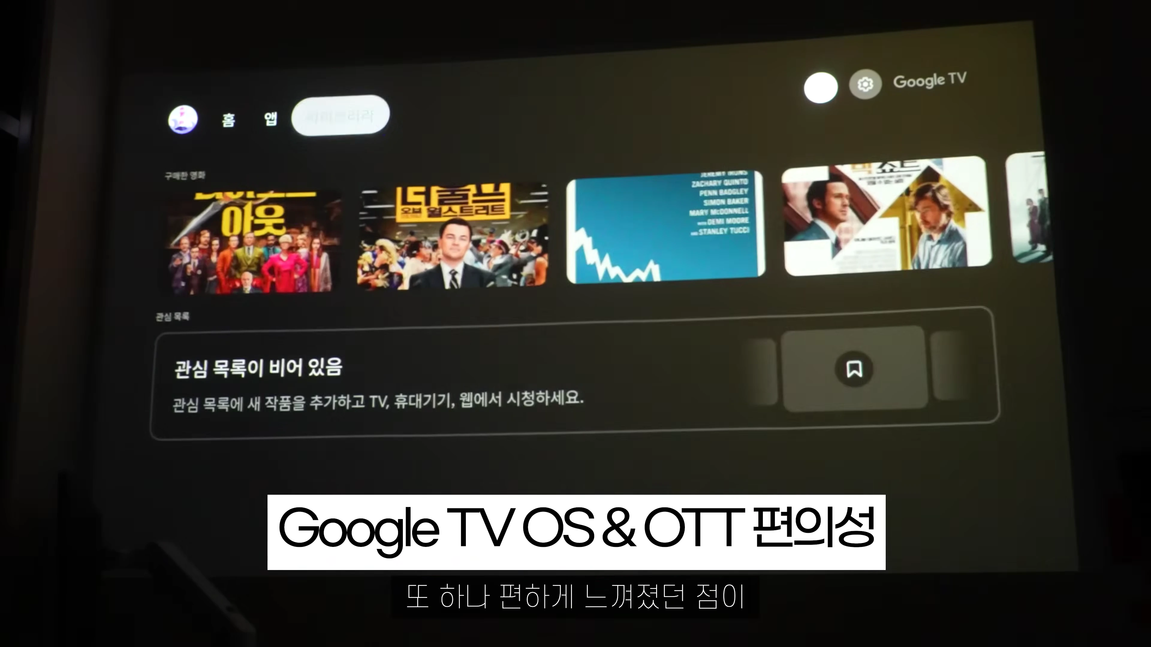 구글 TV OS 인터페이스가 투사된 화면과 하단에 자막이 표시된 모습