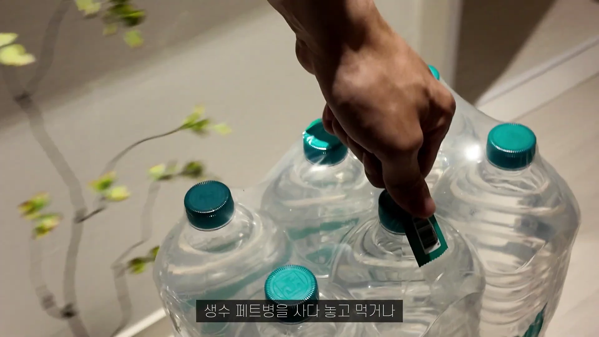 한 손으로 생수 페트병 묶음을 들어 올리는 모습이 담긴 영상 캡처 화면