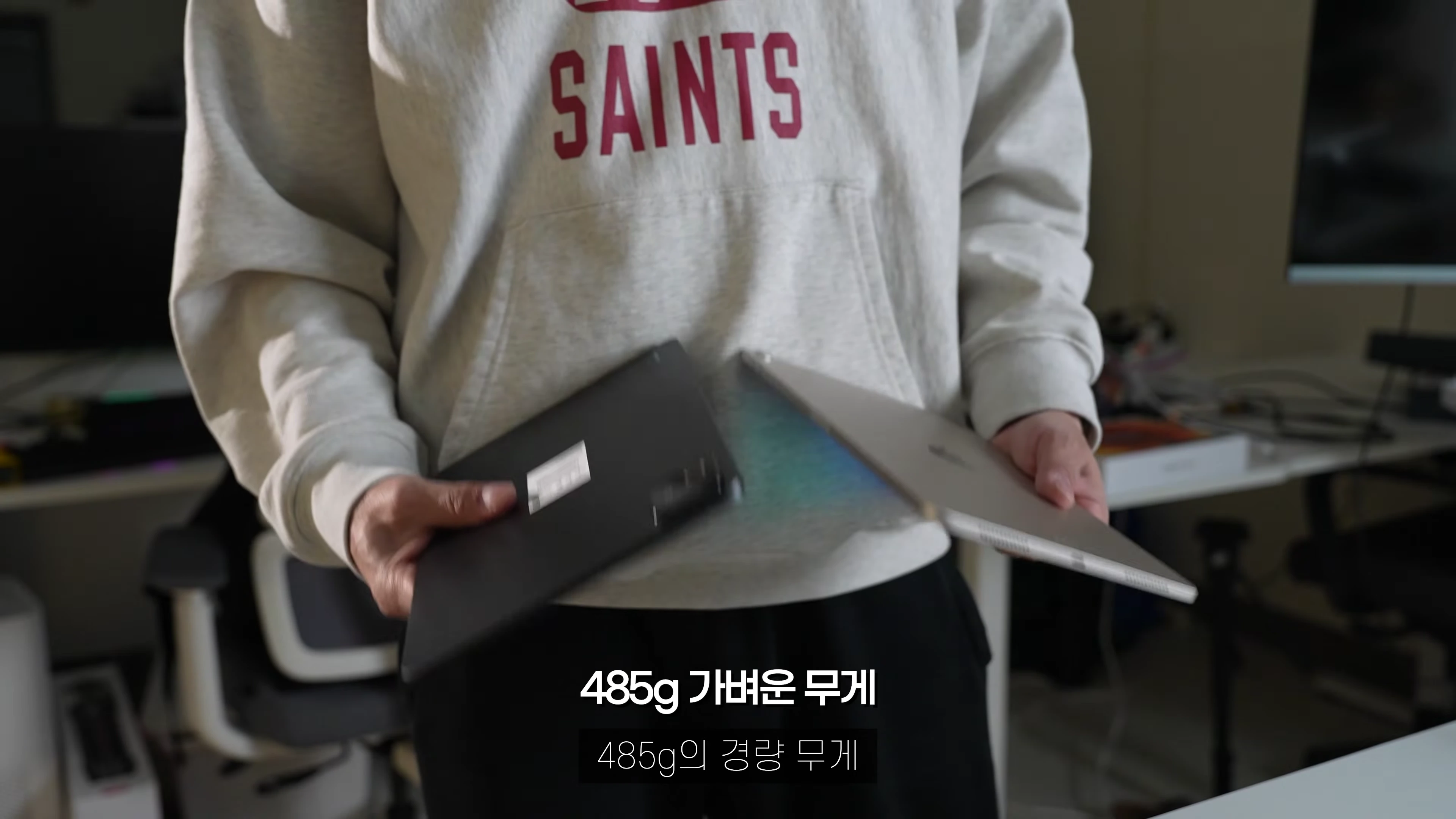 후드티를 입은 사람이 양손에 태블릿 두 대를 들고 있는 모습