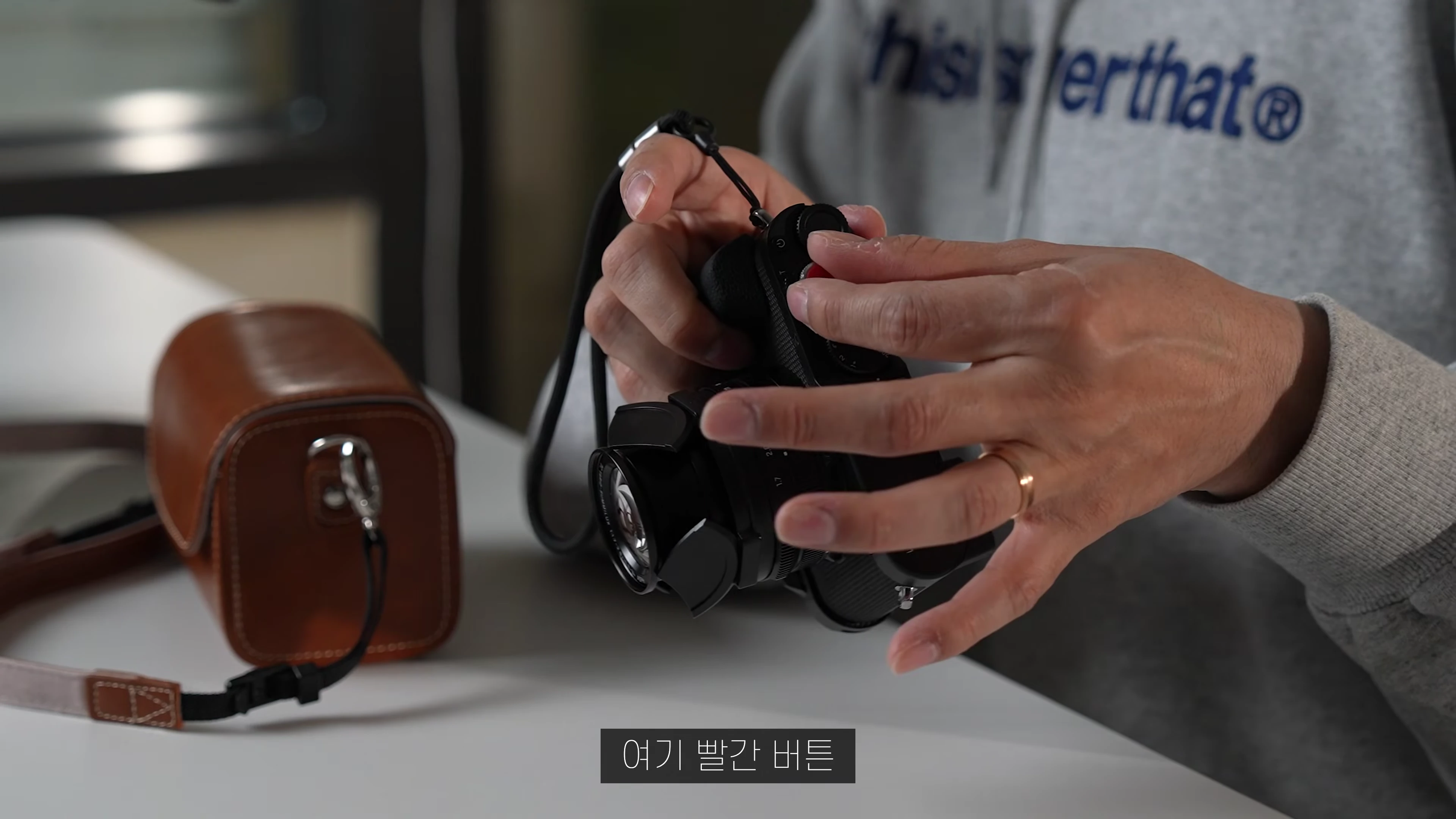 한 사람이 라이카 D-Lux 8 카메라의 셔터 버튼을 조작하고 있는 모습