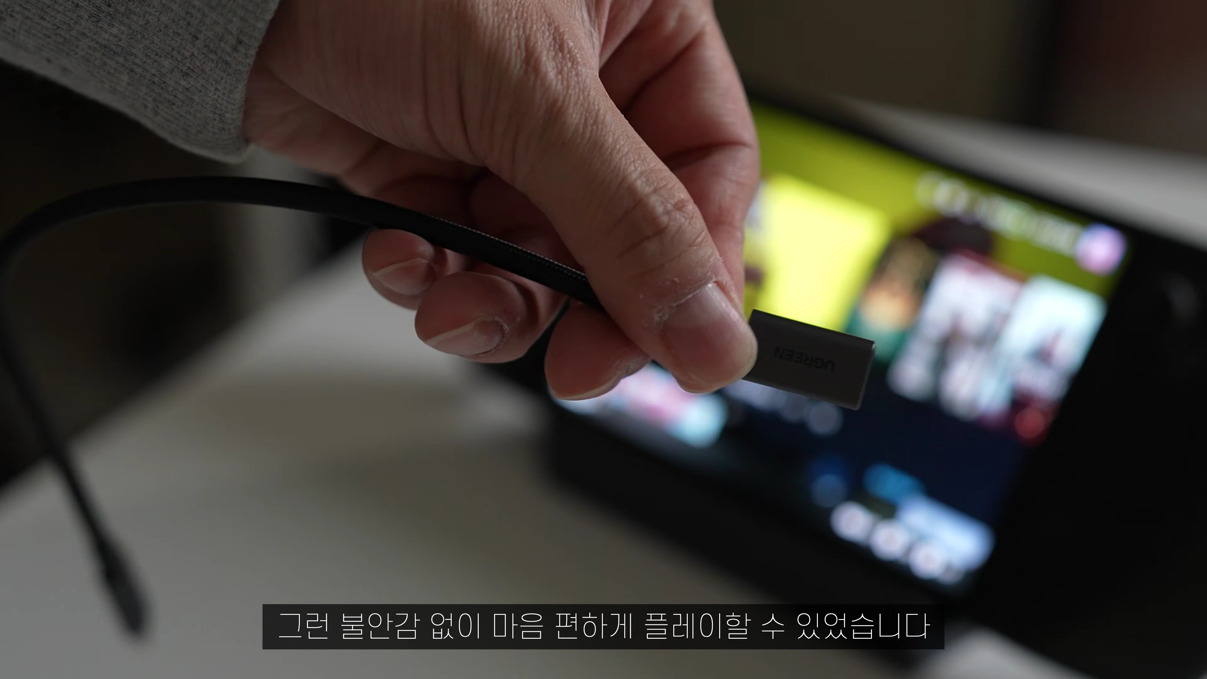 손으로 유그린 로고가 새겨진 USB-C 케이블 단자를 들고 있는 모습
