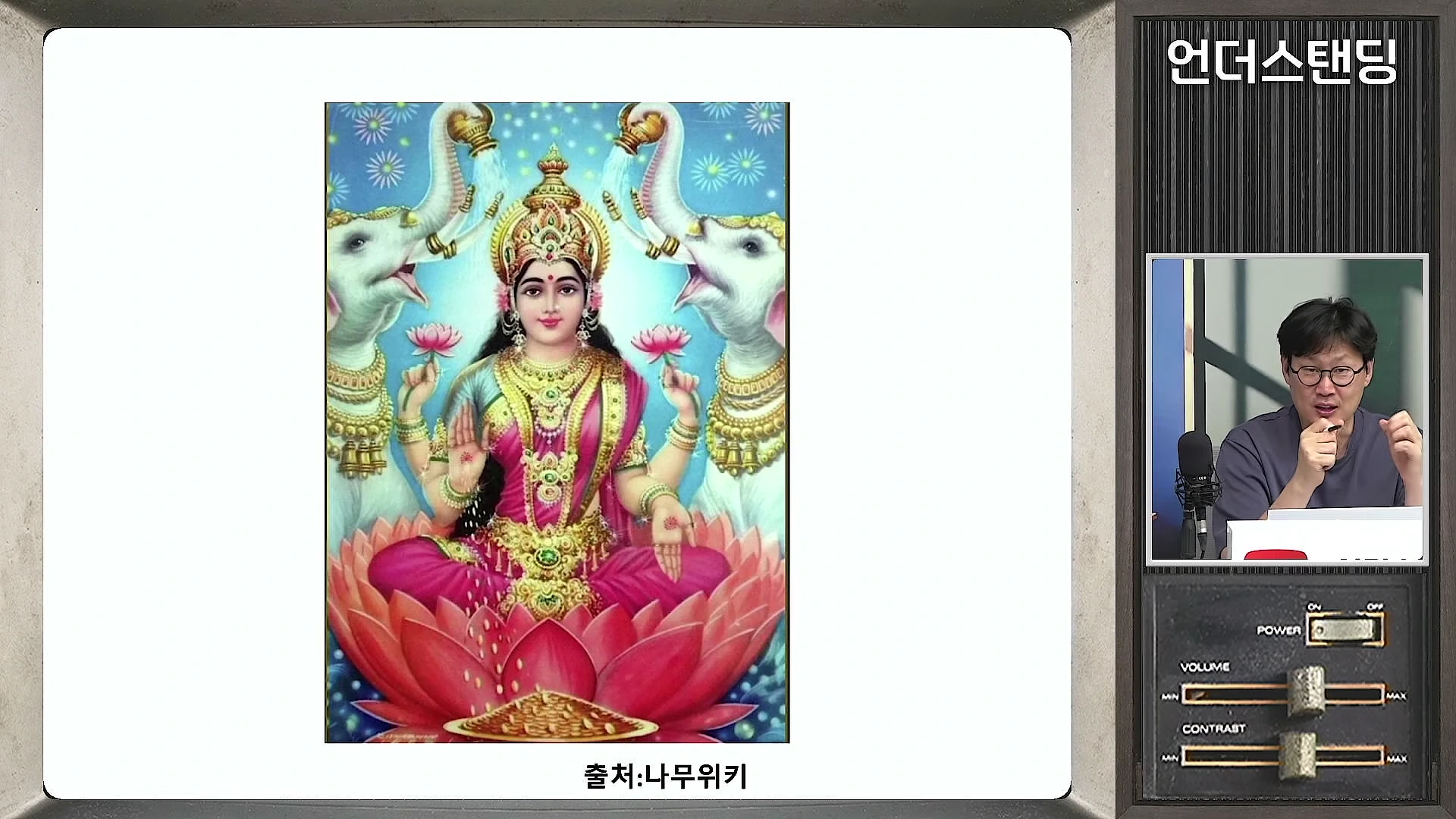 연꽃 위에 앉아 금 장신구를 두른 락슈미 여신 그림과 이를 설명하는 남성 출연자의 모습