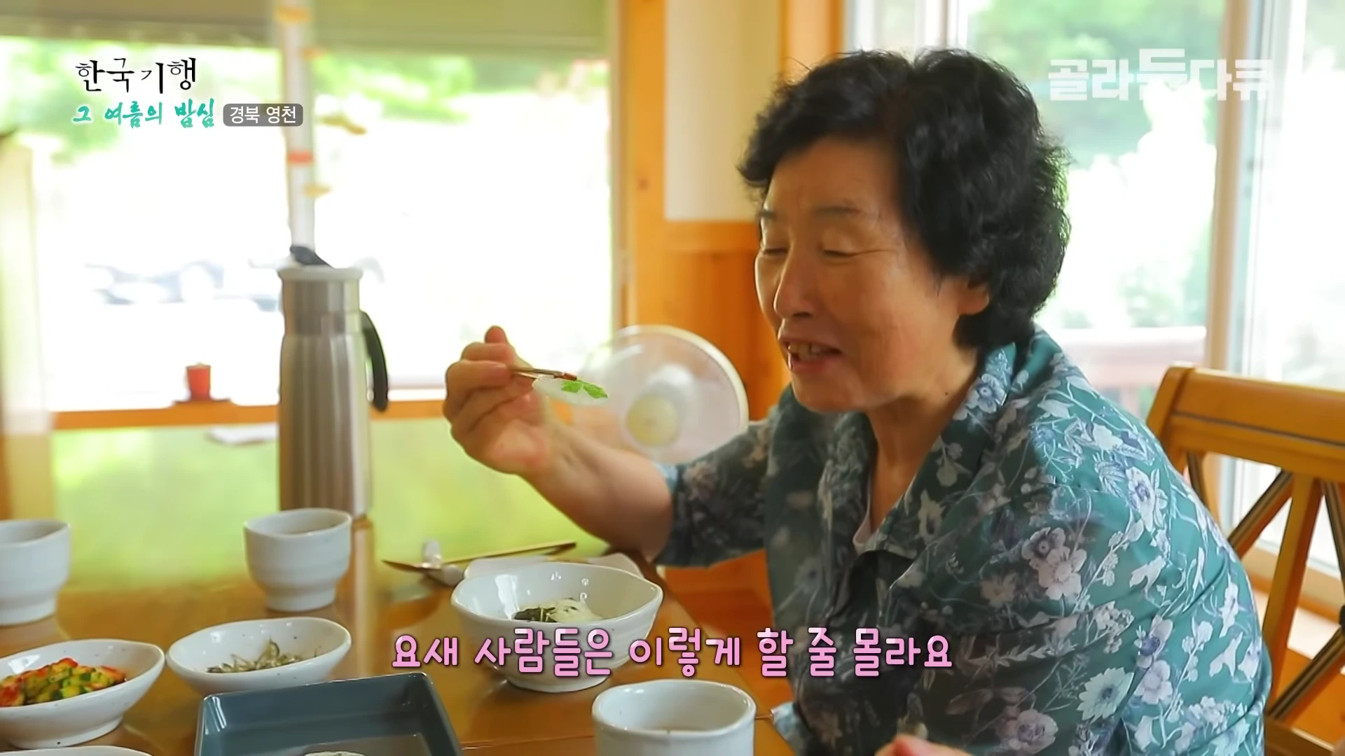 꽃 모양이 장식된 떡을 젓가락으로 집어 들고 환하게 웃고 있는 중년 여성