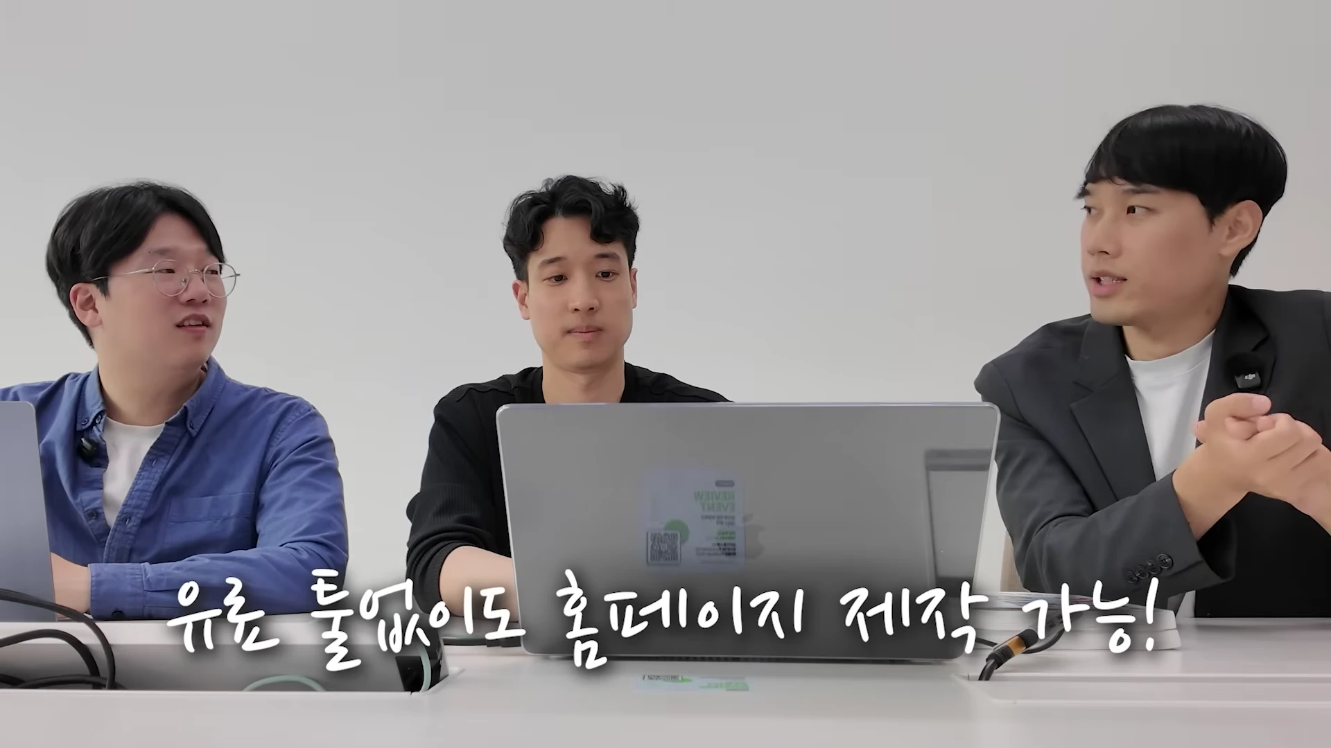 세 명의 남성이 노트북을 앞에 두고 앉아 대화를 나누는 스튜디오 인터뷰 장면