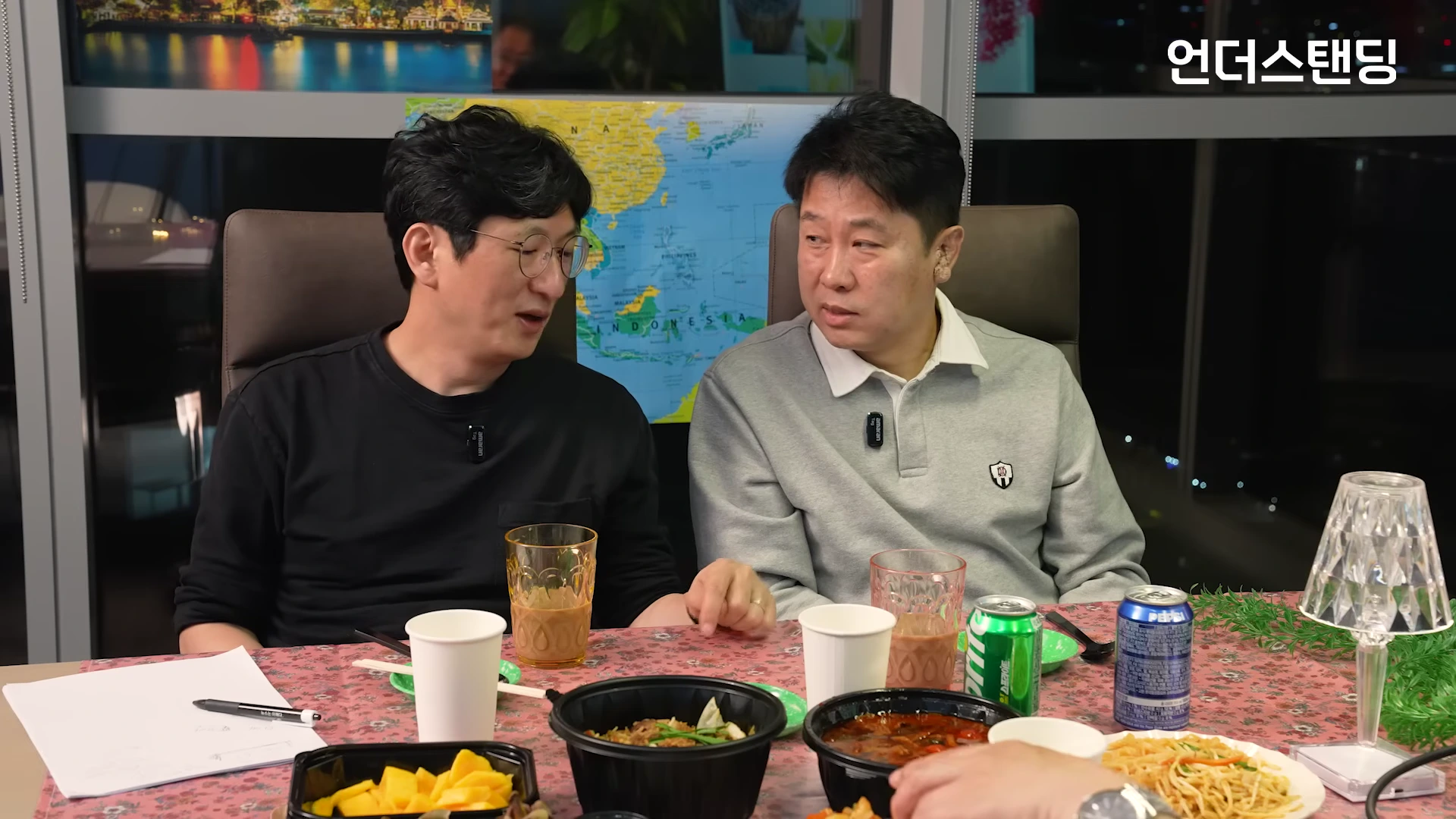 스튜디오 테이블에 앉아 대화를 나누는 두 남성과 그 앞에 놓인 다양한 음식들