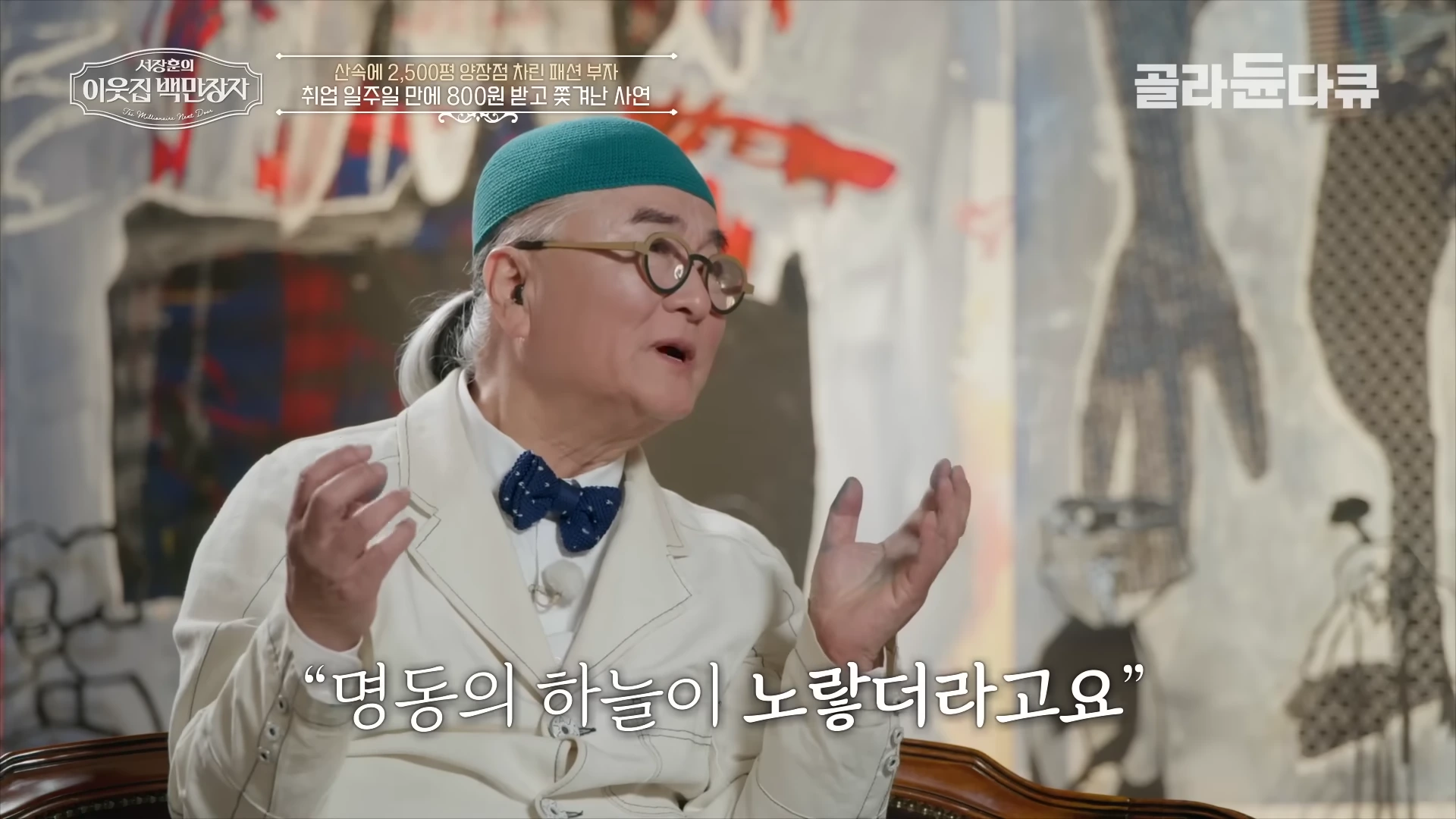 초록색 모자를 쓰고 안경을 쓴 남성이 손을 들어 이야기하는 모습이 담긴 방송 화면
