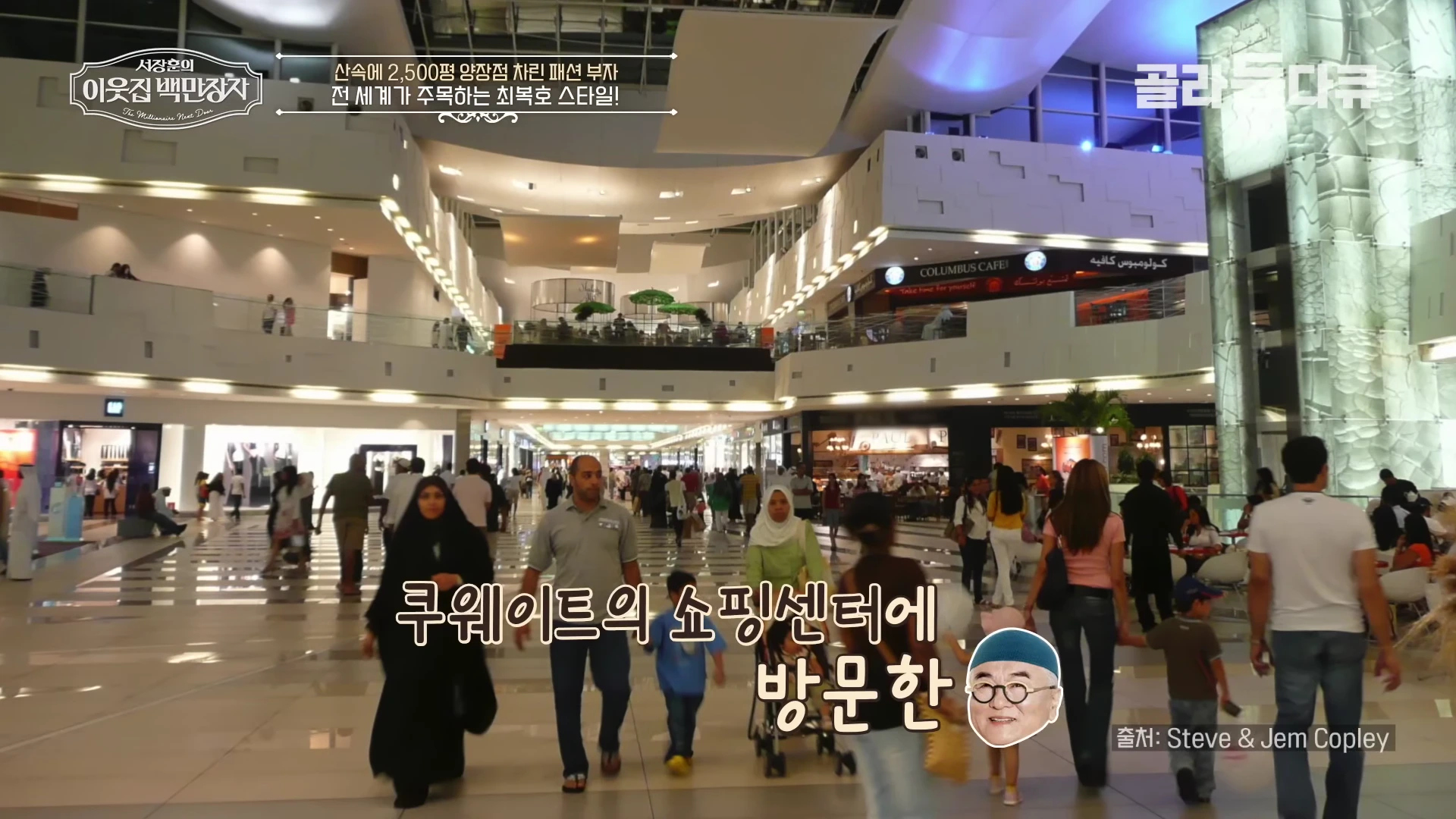 쿠웨이트의 대형 쇼핑센터 내부를 걷는 사람들과 매장들이 보이는 영상 화면