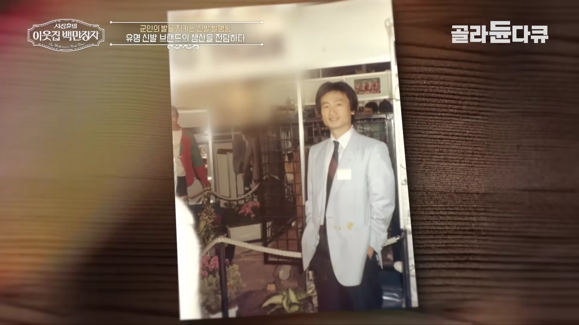 젊은 시절 정장을 입고 서 있는 남성의 모습이 담긴 오래된 사진 액자