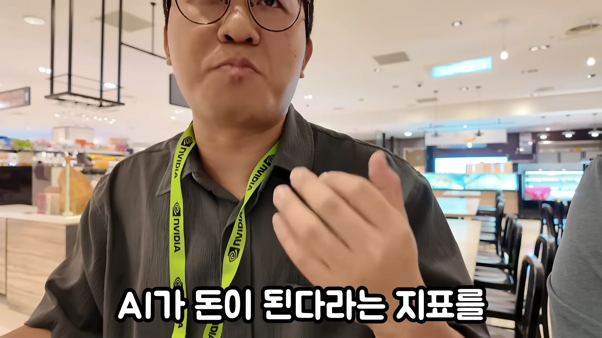 엔비디아 로고가 새겨진 목걸이를 착용한 남성이 실내에서 대화하고 있는 모습