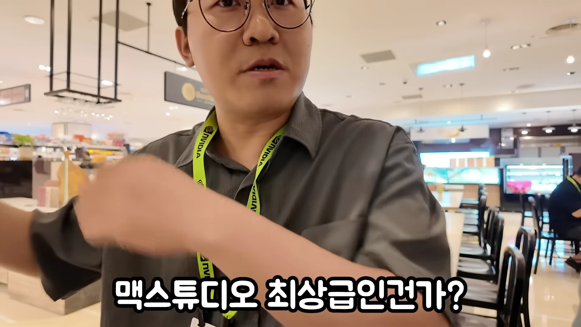 안경을 쓴 남성이 엔비디아 로고가 새겨진 목걸이를 걸고 실내에서 대화하는 모습