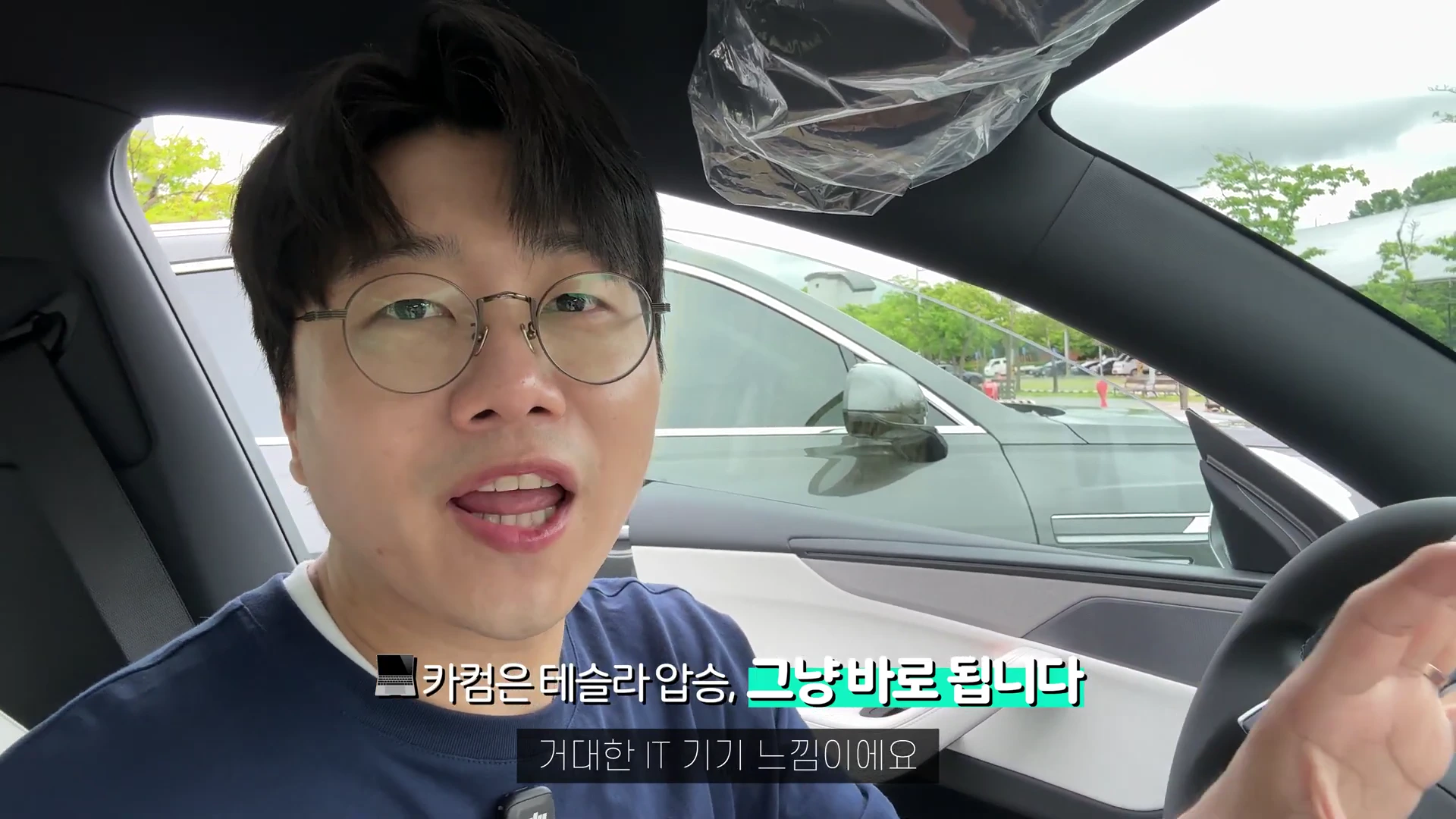 안경을 쓴 남성이 차량 운전석에 앉아 카메라를 보며 이야기를 나누고 있다.