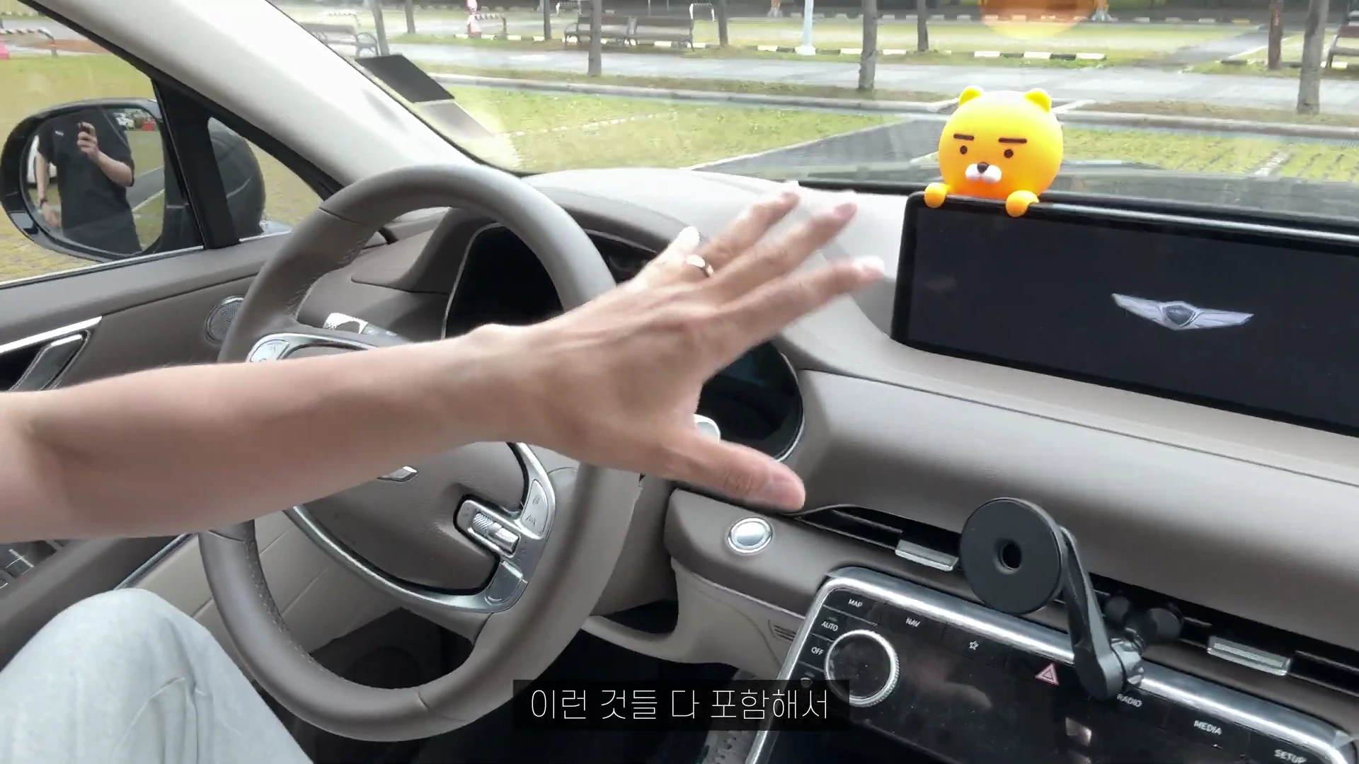 자동차 운전석에서 손을 뻗어 대시보드와 스티어링 휠 주변을 가리키는 모습