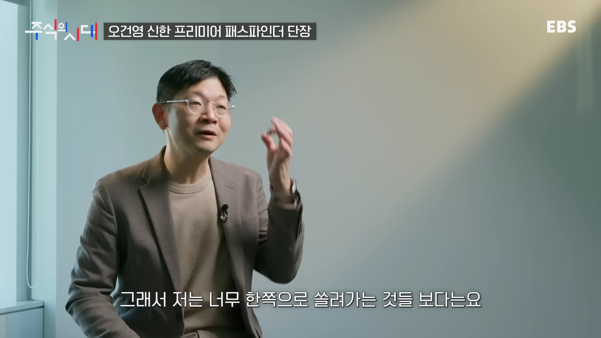 안경을 쓴 남성이 인터뷰 중 손짓하며 이야기하는 모습이 담긴 방송 화면
