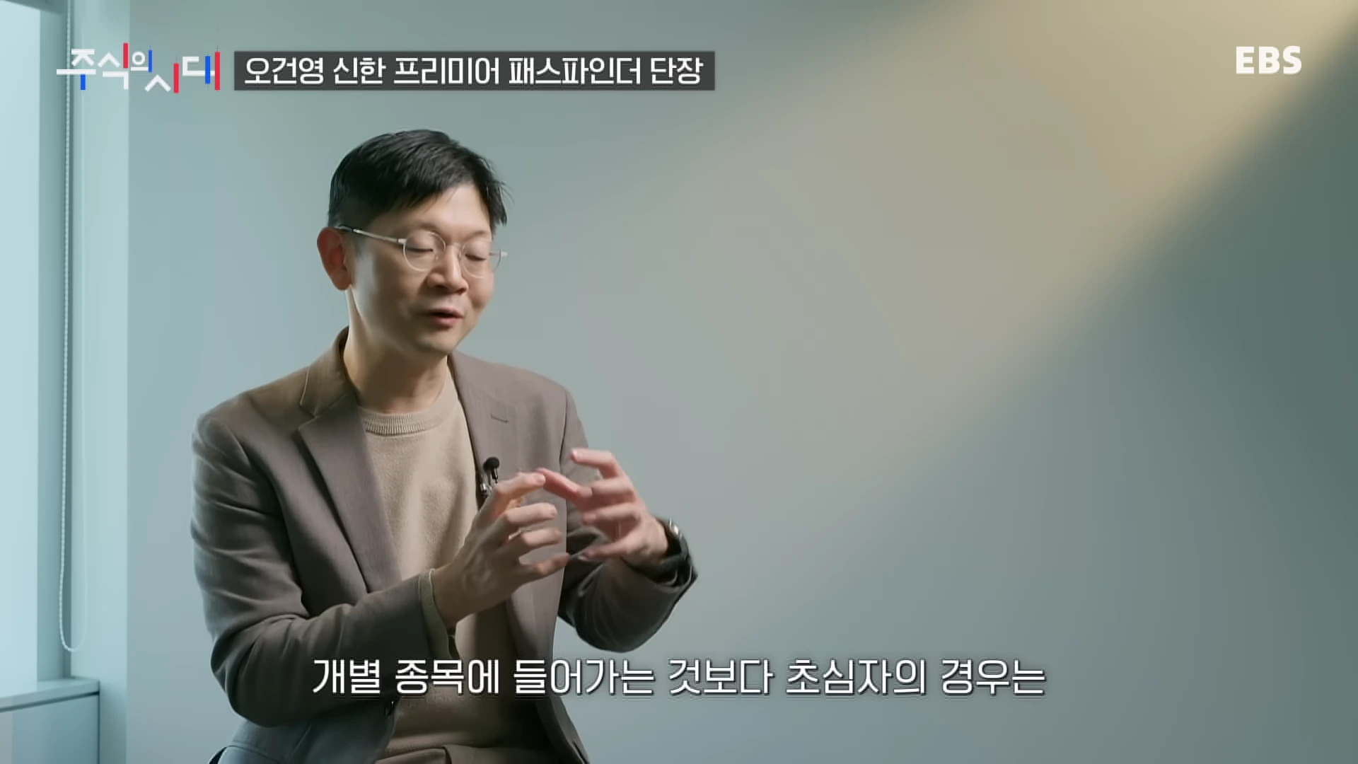 안경을 쓴 남성이 인터뷰 중 손동작을 하며 설명하고 있는 모습