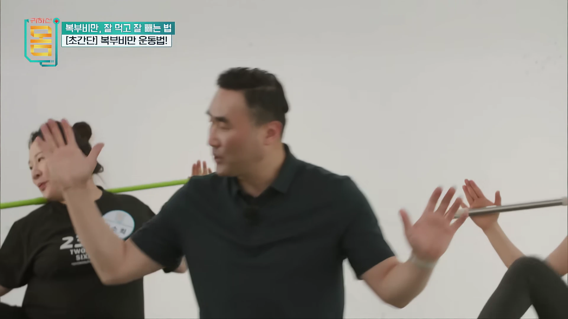 운동복을 입은 남성이 실내에서 사람들에게 운동 동작을 가르치고 있는 모습