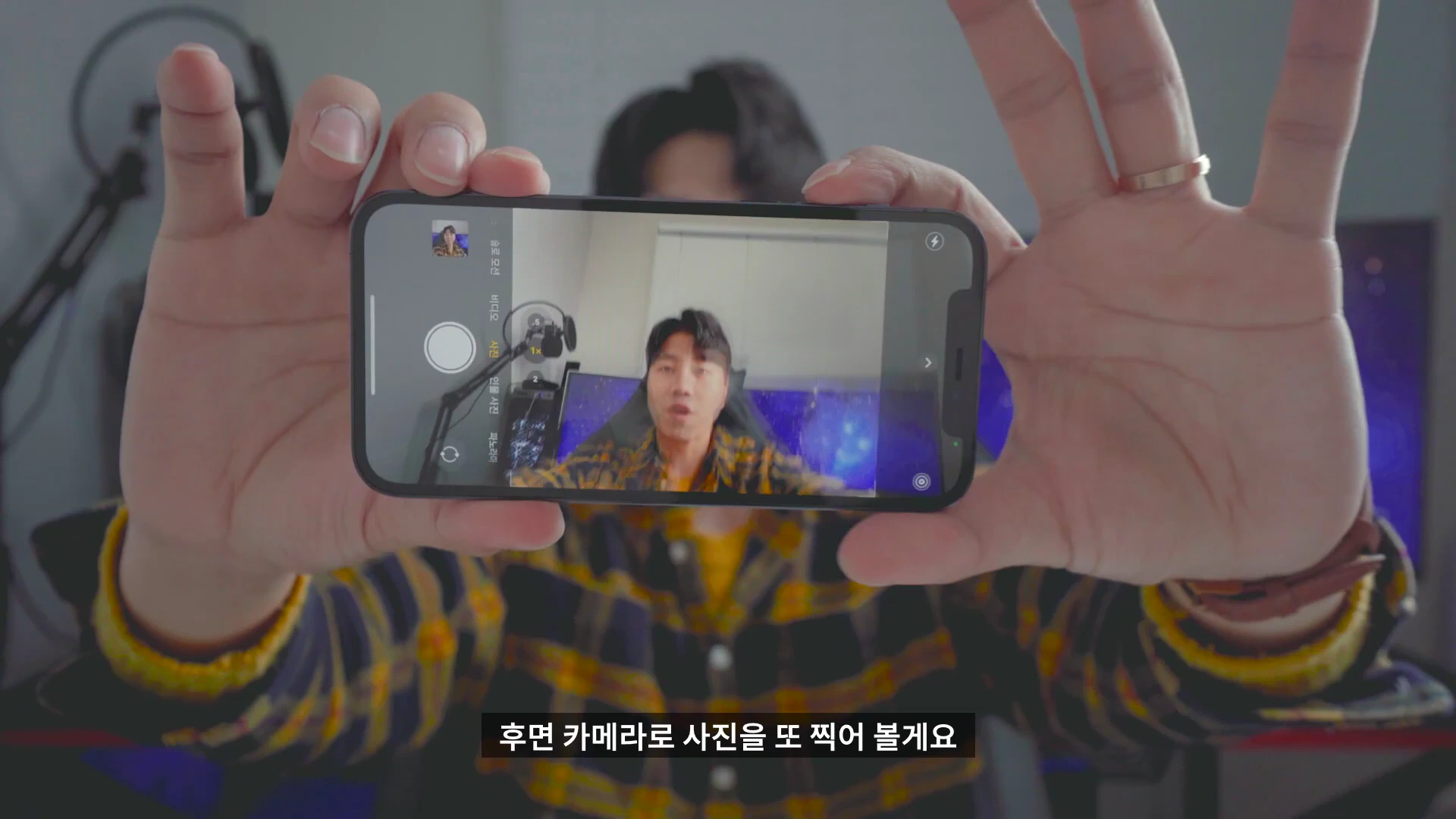 한 남성이 양손으로 아이폰을 들어 카메라 앱 화면을 보여주고 있는 모습