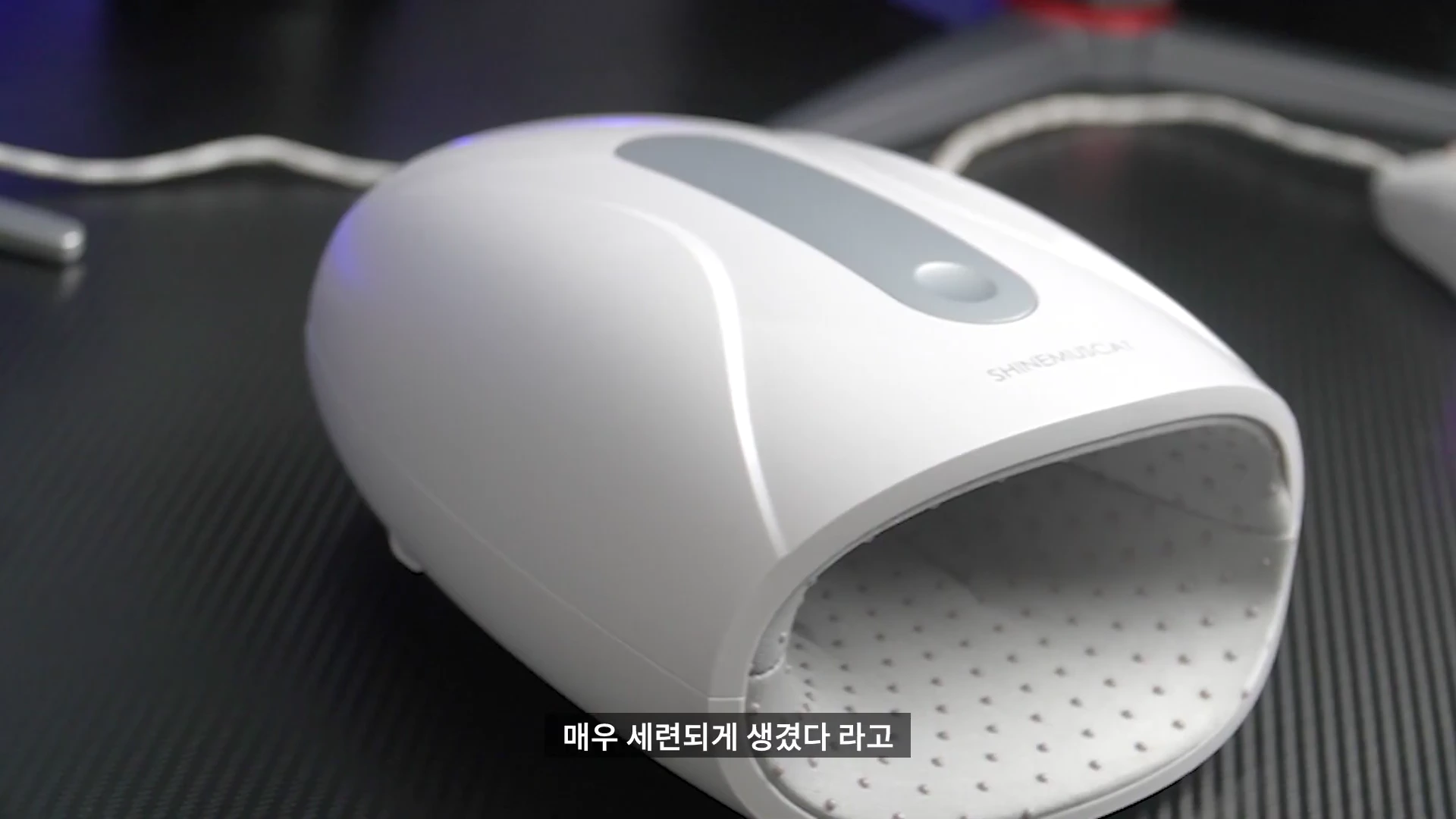 책상 위에 놓인 흰색과 은색 조합의 세련된 디자인을 가진 휴대용 손 마사지기