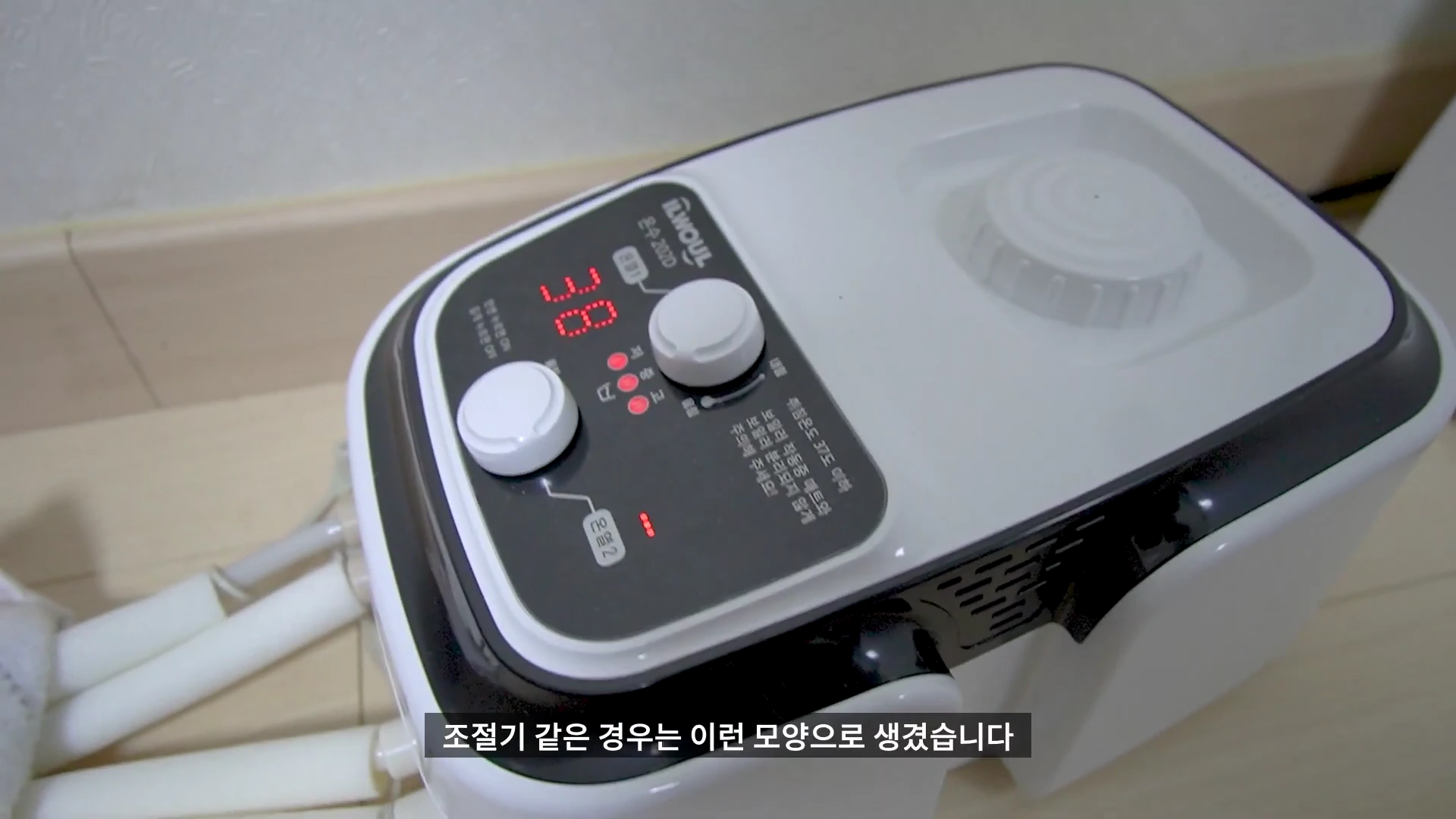 온수매트의 온도 조절기 본체가 바닥에 놓여 있고, 디지털 화면에 38이라는 숫자가 표시되어 있다.