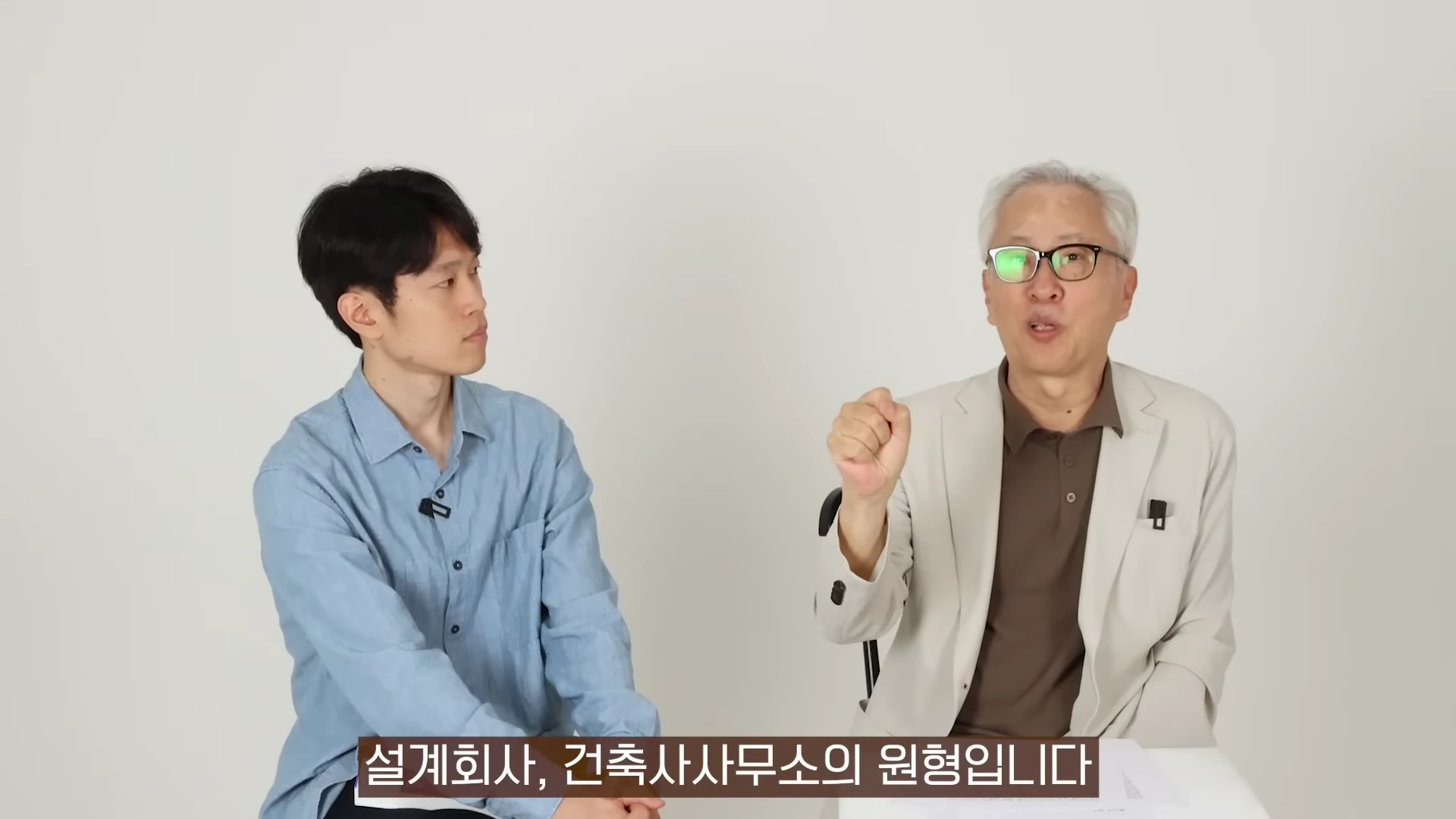 밝은 배경 앞에서 두 남성이 대화를 나누고 있으며, 하단에는 '설계회사, 건축사사무소의 원형입니다'라는 자막이 표시되어 있습니다.
