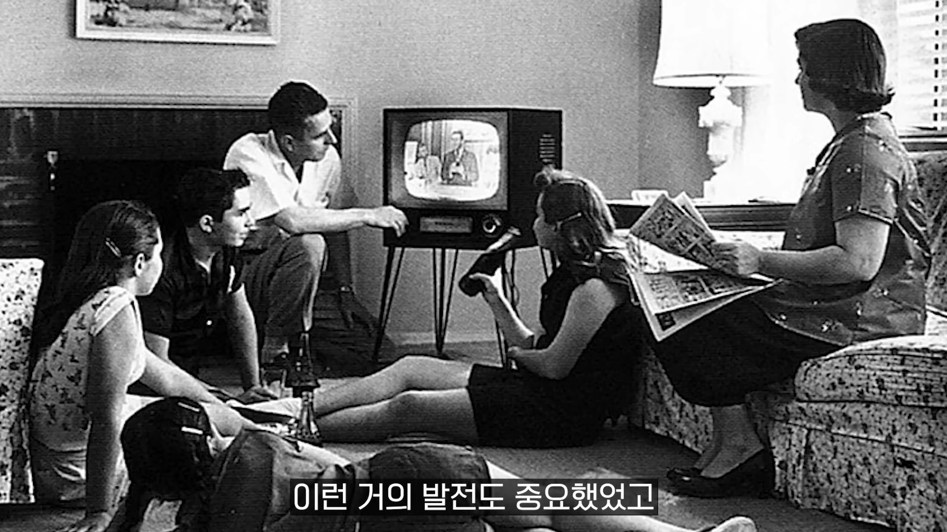 거실에 모여 앉아 텔레비전을 시청하는 가족들의 흑백 사진