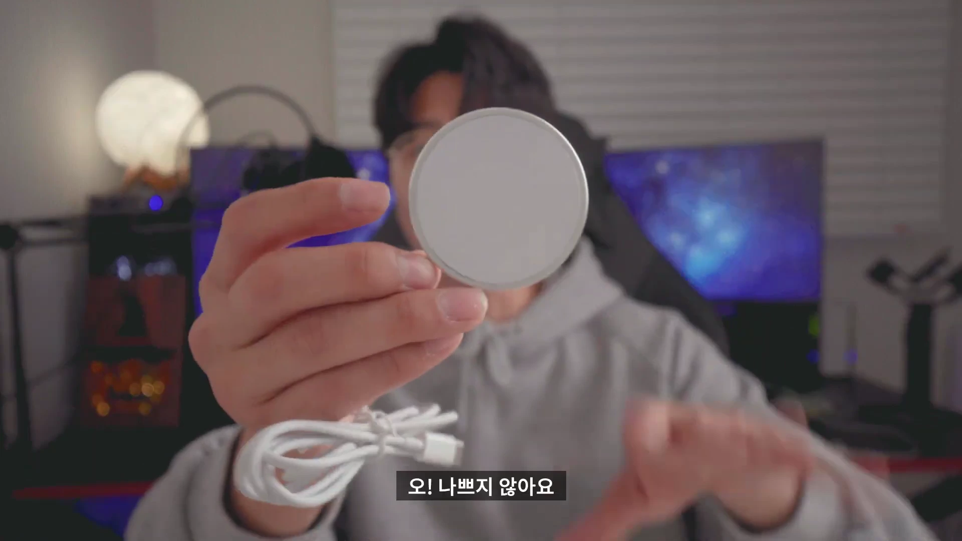 한 남성이 손에 든 원형의 흰색 마그네틱 무선 충전기를 카메라 쪽으로 보여주고 있다.