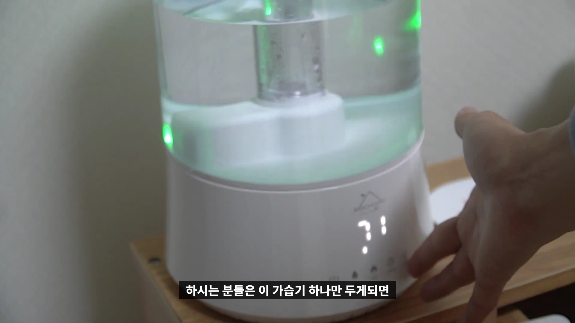투명한 물통과 LED 조명이 켜진 흰색 복합식 가습기 본체를 손으로 조작하는 모습