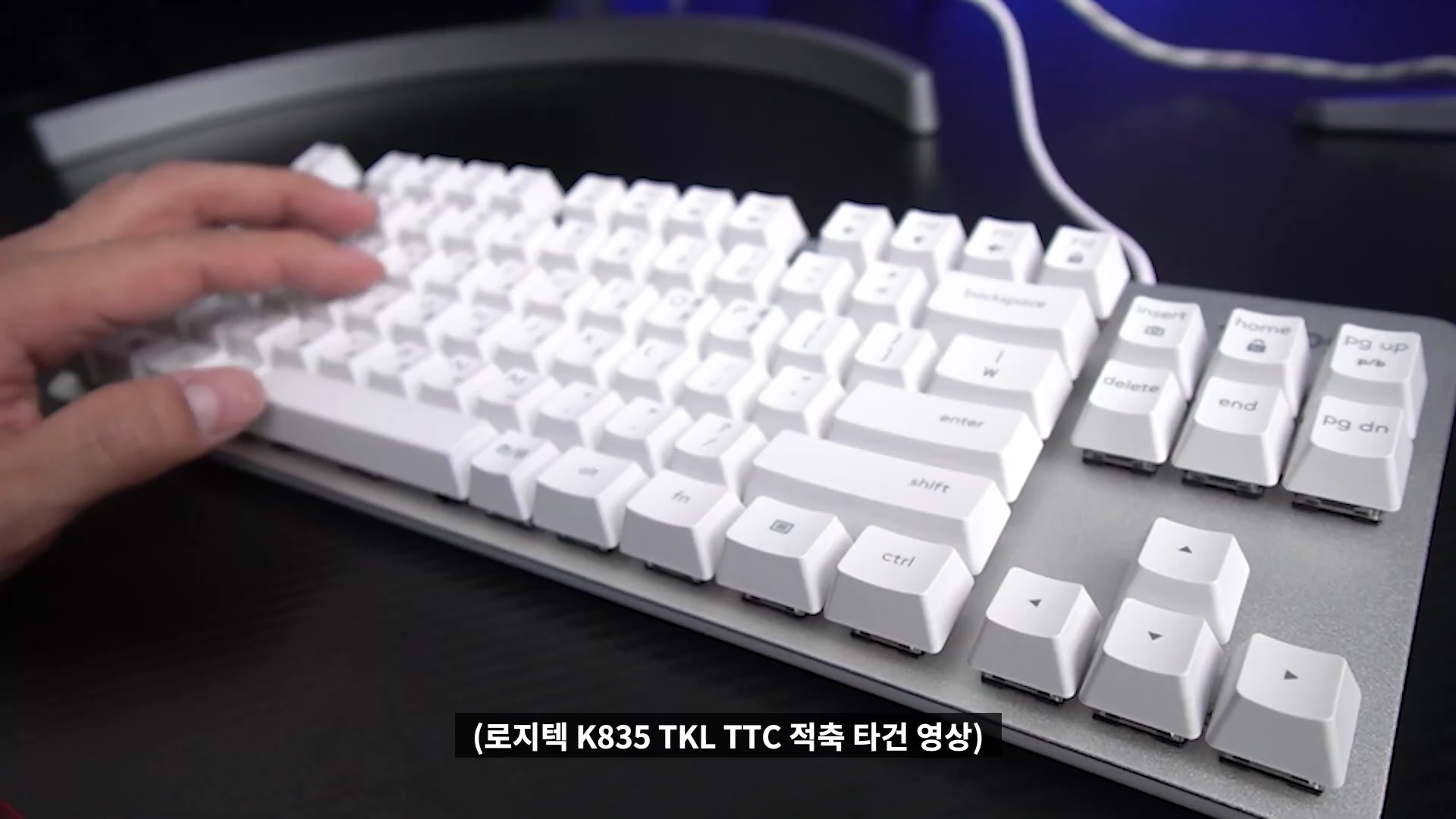 흰색 키캡이 장착된 로지텍 텐키리스 기계식 키보드를 손으로 타건하는 모습