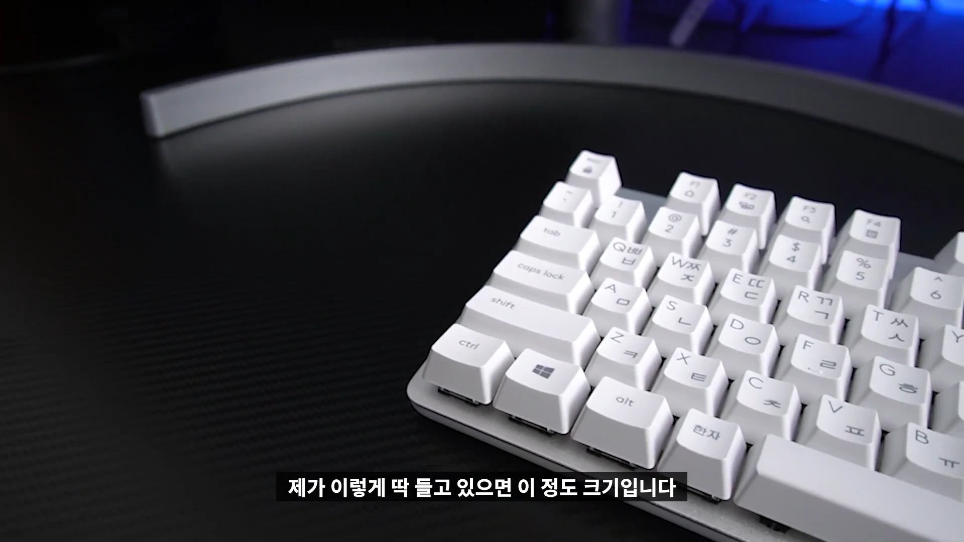 검은색 책상 위에 놓인 오픈 화이트 색상의 텐키리스 기계식 키보드