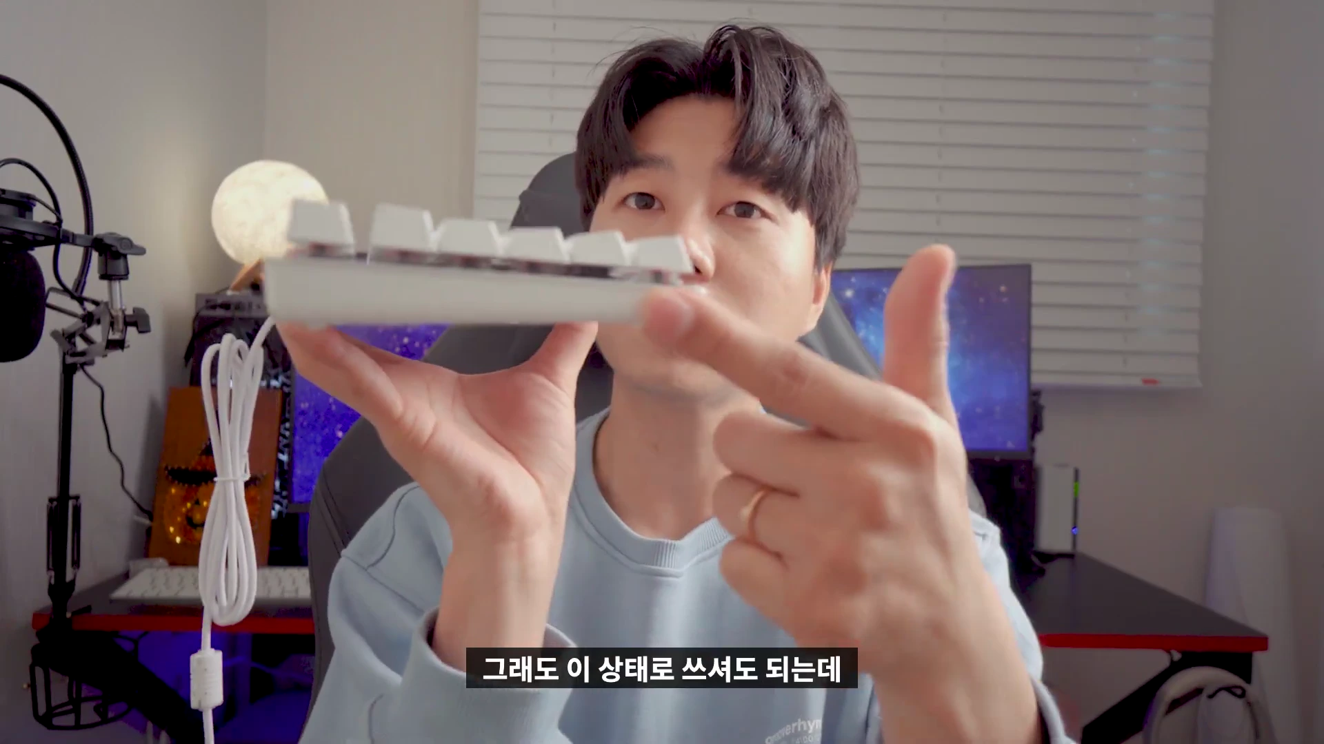 한 남성이 손에 흰색 기계식 키보드를 들고 측면 각도를 보여주고 있는 모습