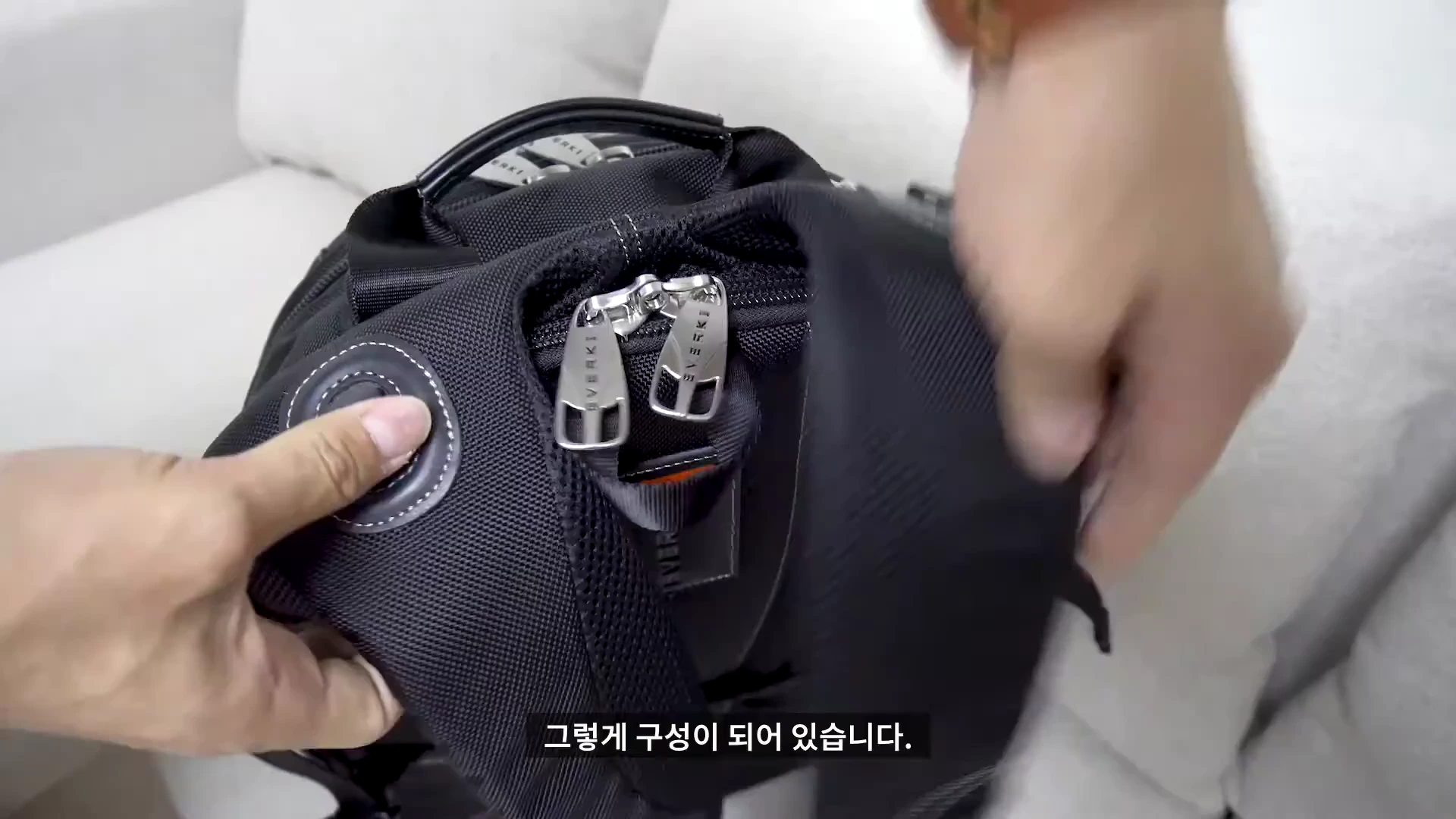 검은색 백팩의 지퍼를 손으로 열고 있는 모습
